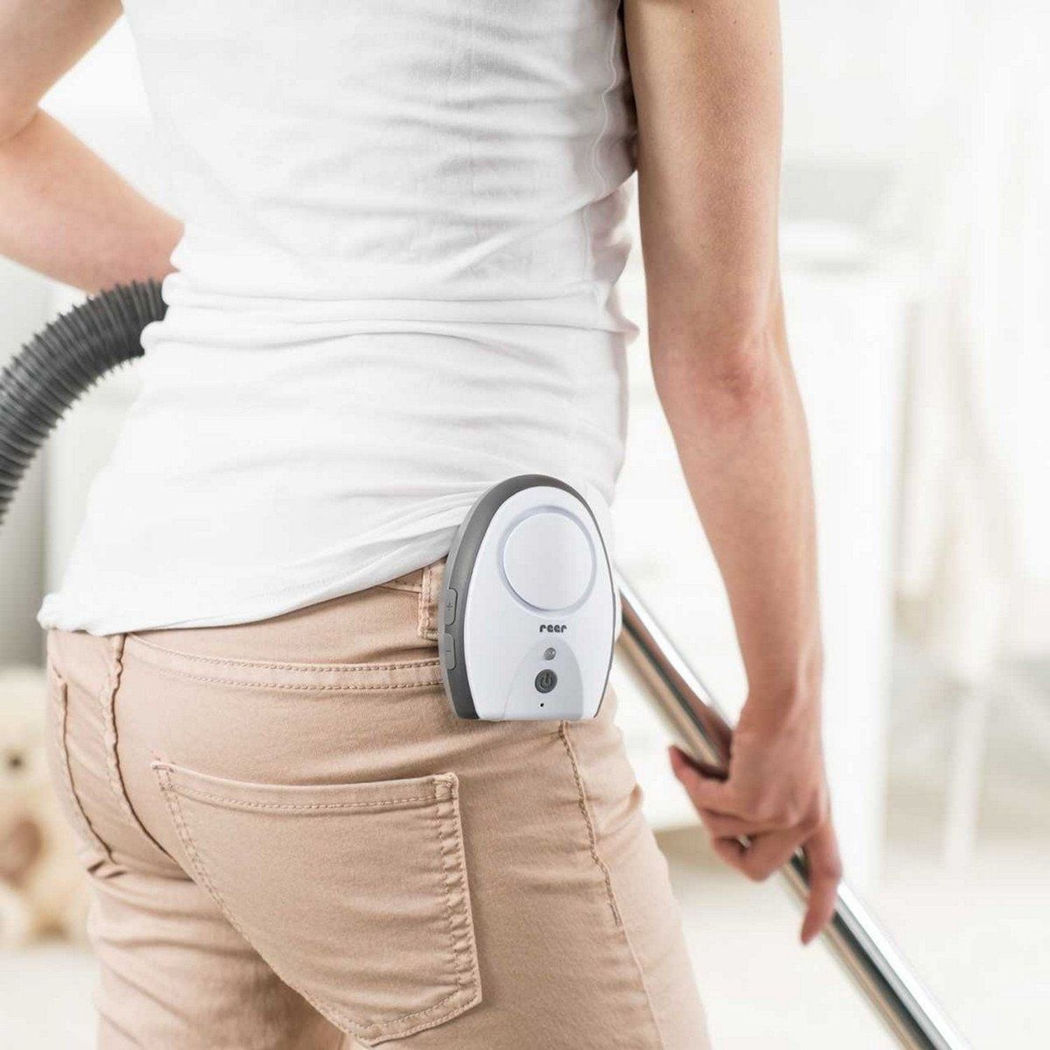 Ein Babyfon ist am Hosenbund einer Person befestigt, die einen Staubsauger benutzt.