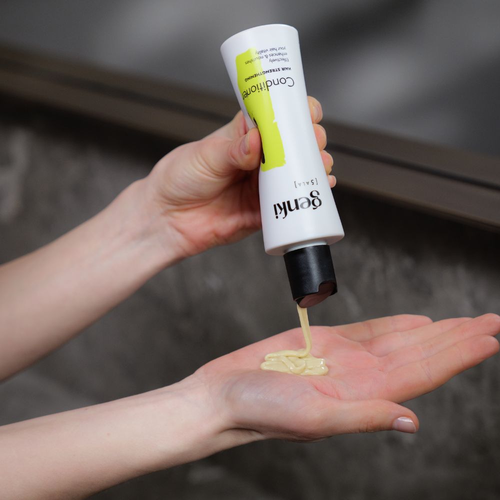 Conditioner wird in die Hand gegossen. Gelbliche Flüssigkeit. Genki-Logo und Produktbezeichnung auf der Flasche.