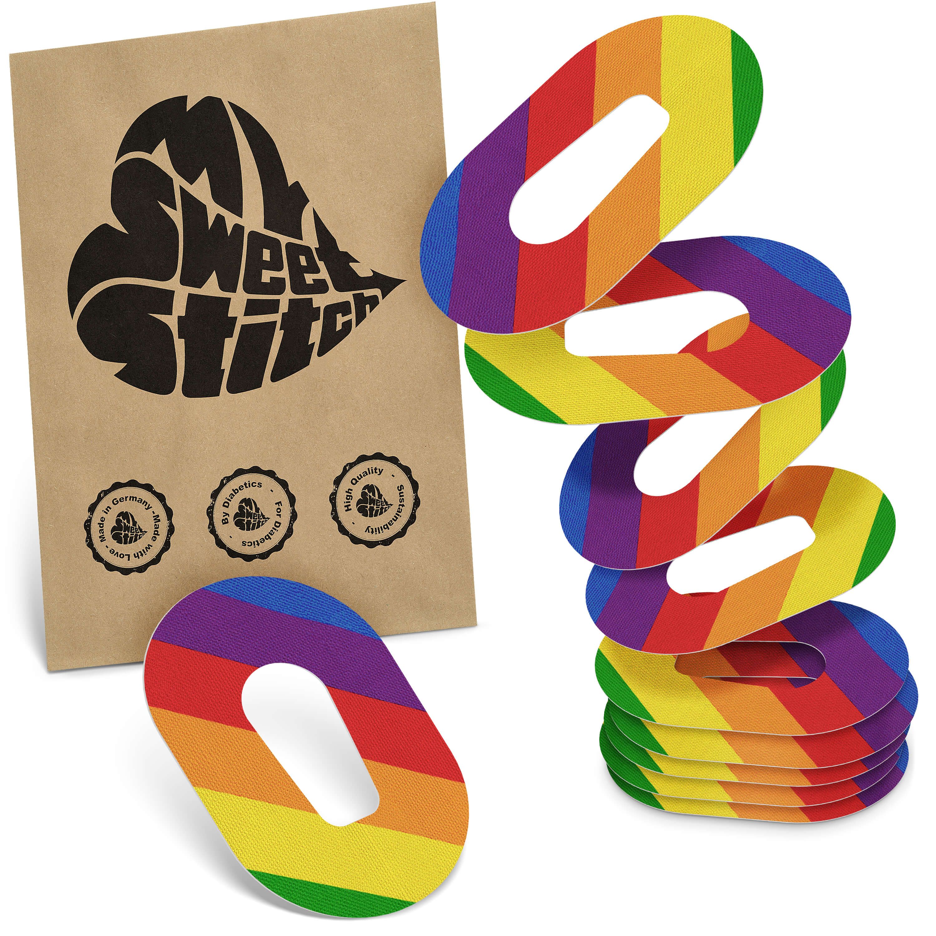 Fixierpflaster mit Regenbogenmuster und Aussparung. Braune Verpackung mit Logo 'MySweetStitch'. Mehrere Pflaster gestapelt.