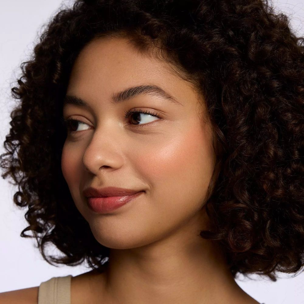 Porträt einer Frau mit Rouge auf den Wangen. Dunkle Locken. Blick zur Seite.