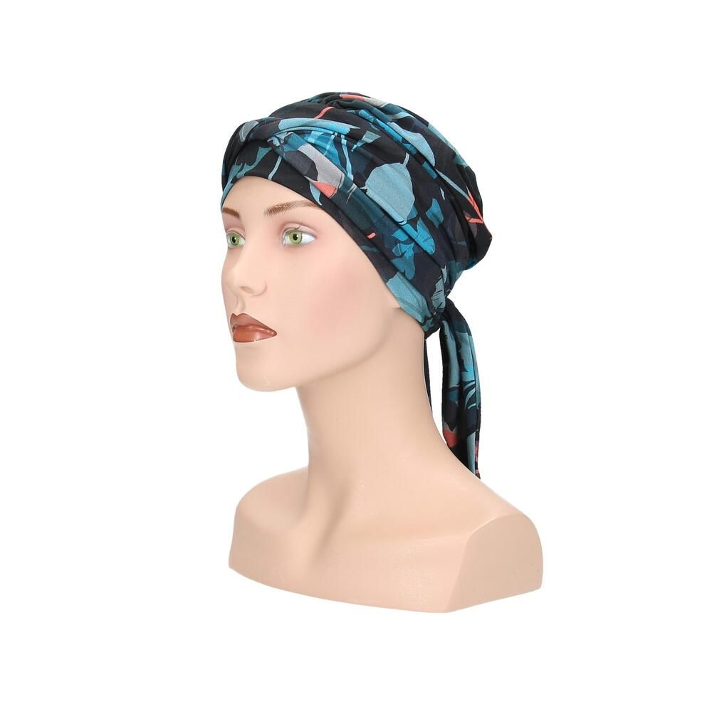 Turban Letti, floral bedruckt, auf einer Büste. Farben: Schwarz, Türkis, Rosa. Stoff mit Falten. Seitenansicht mit Schleife.