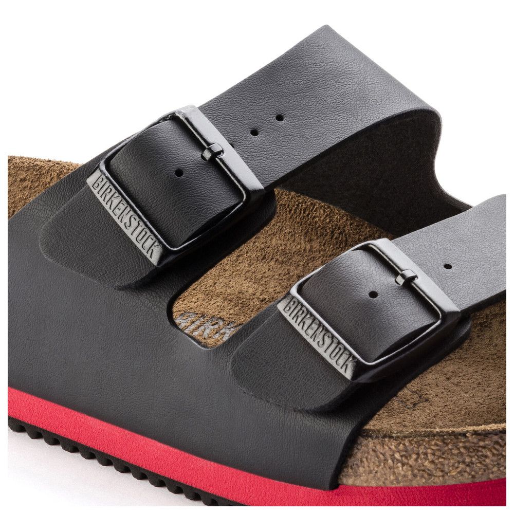 Detailansicht der Schnalle einer schwarzen Sandale. Birkenstock-Logo auf der Schnalle.