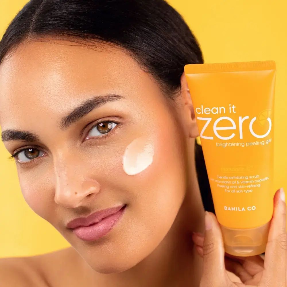 Frau mit Produkt auf dem Gesicht. Gelbe Tube mit 'clean it zero' in der Hand. Gelbe Kappe.
