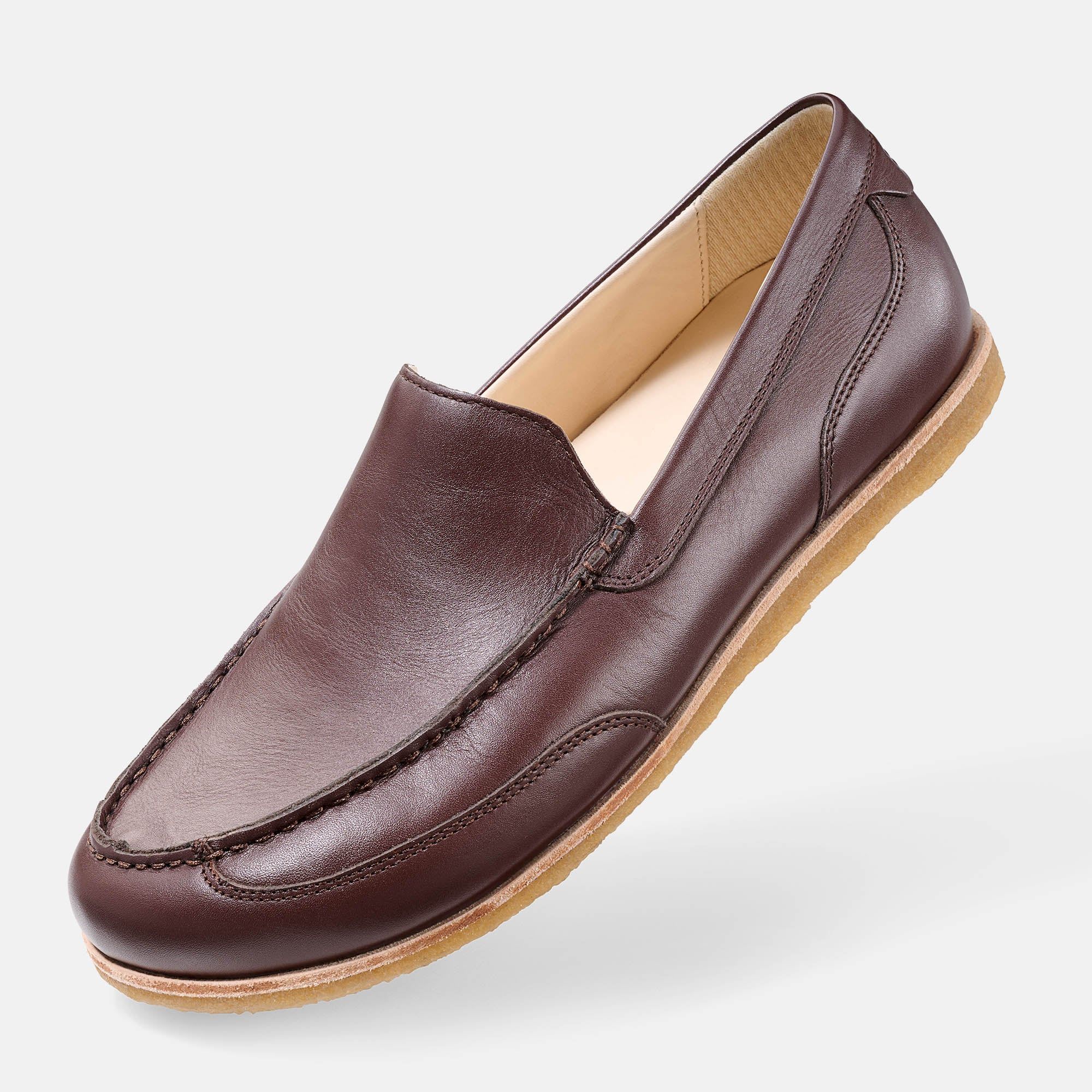 Brauner Leder-Slipper. Hellbraune Sohle. Nahtdetails. Schuh schräg von vorne.