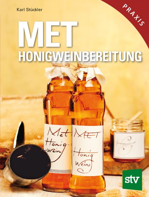 Buchcover mit Titel MET Honigweinbereitung. Zwei Flaschen Honigwein, Etiketten mit MET Honigwein. Im Hintergrund ein Glas Honig.