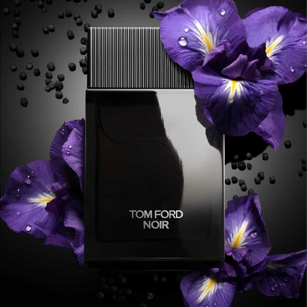 Schwarzer Flakon mit schwarzem Deckel. Aufschrift TOM FORD NOIR in Weiß. Umgeben von lila Blüten.