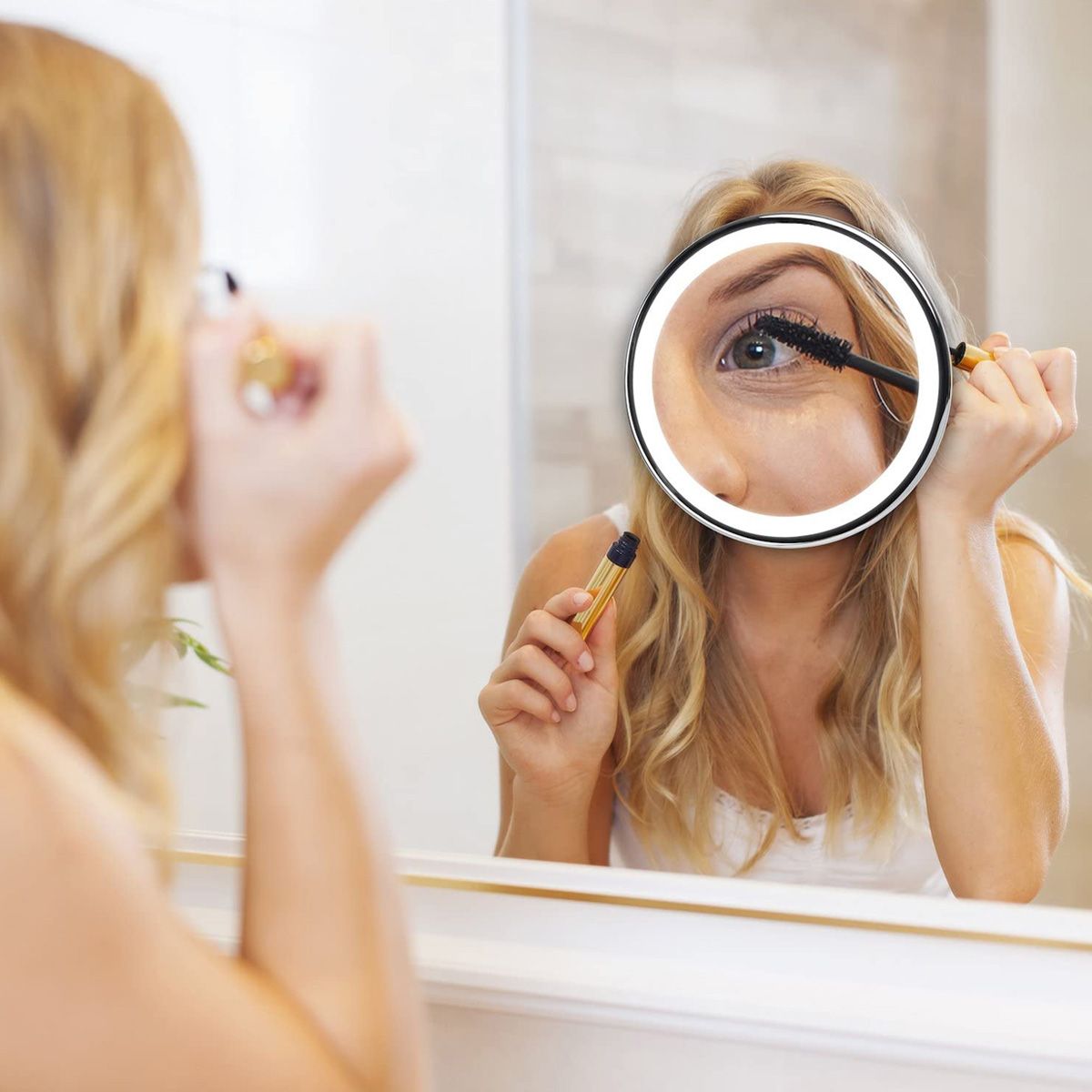 Frau benutzt einen beleuchteten Vergrößerungsspiegel für Make-up.