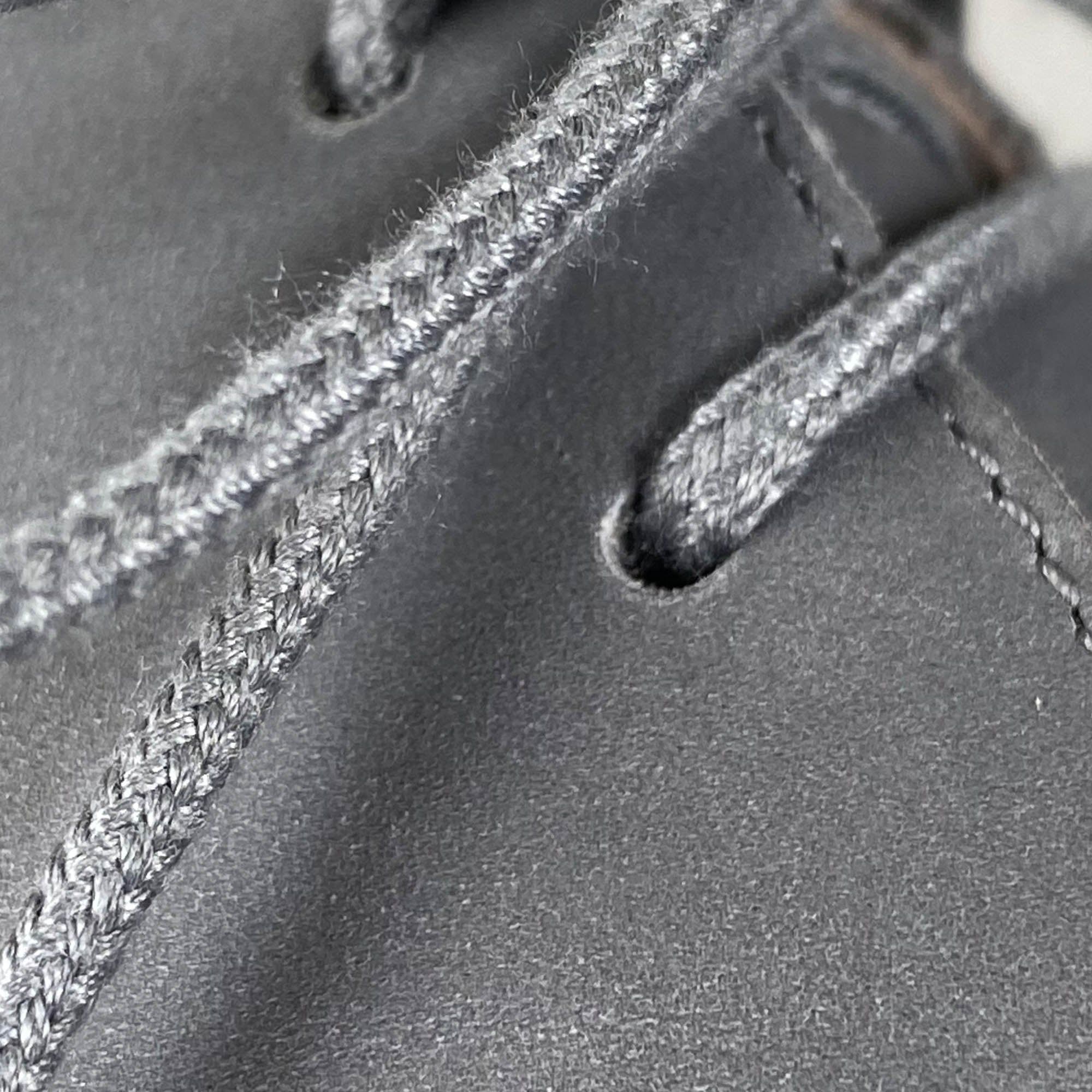 Detailaufnahme eines grauen Schnürschuhs. Schnürsenkel und Ösen sind deutlich zu sehen.