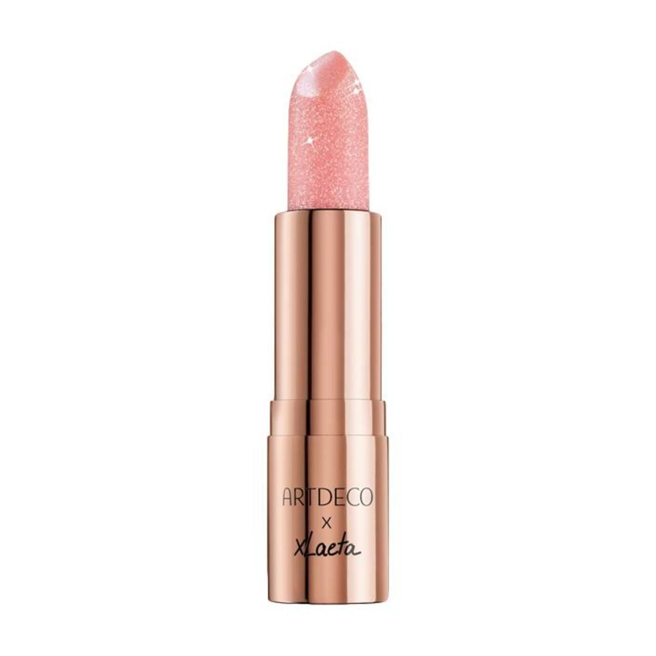 Artdeco Lippenbalsam, rosa Glitzer, offene Hülse. Goldfarbene Hülse mit Schriftzug Artdeco x Laeta.