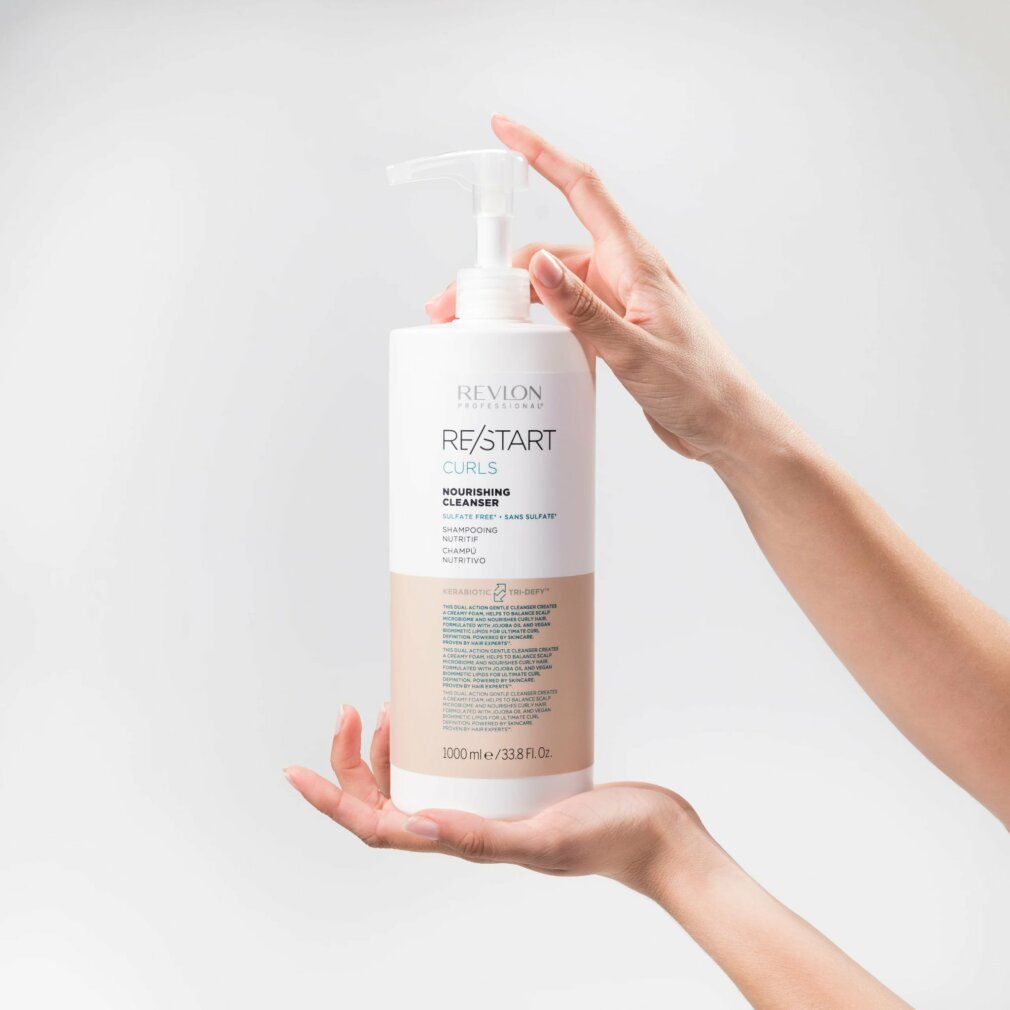 Weißer Flakon mit Pumpe. Aufschrift: Revlon Re-Start Curls. Text in Englisch und Spanisch. Hände halten den Flakon.