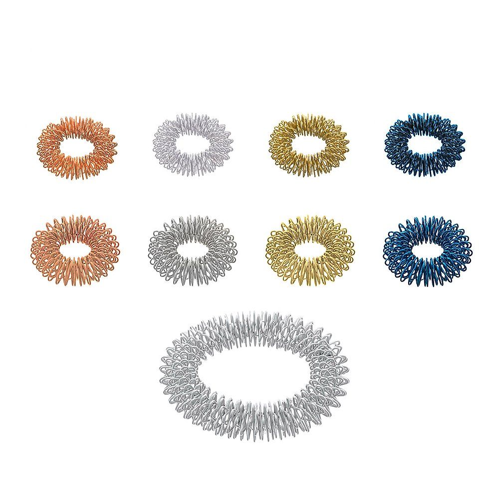 Set aus acht Akupressur-Ringen in Kupfer, Silber, Gold und Blau. Ein großer Ring in Silber liegt unten.