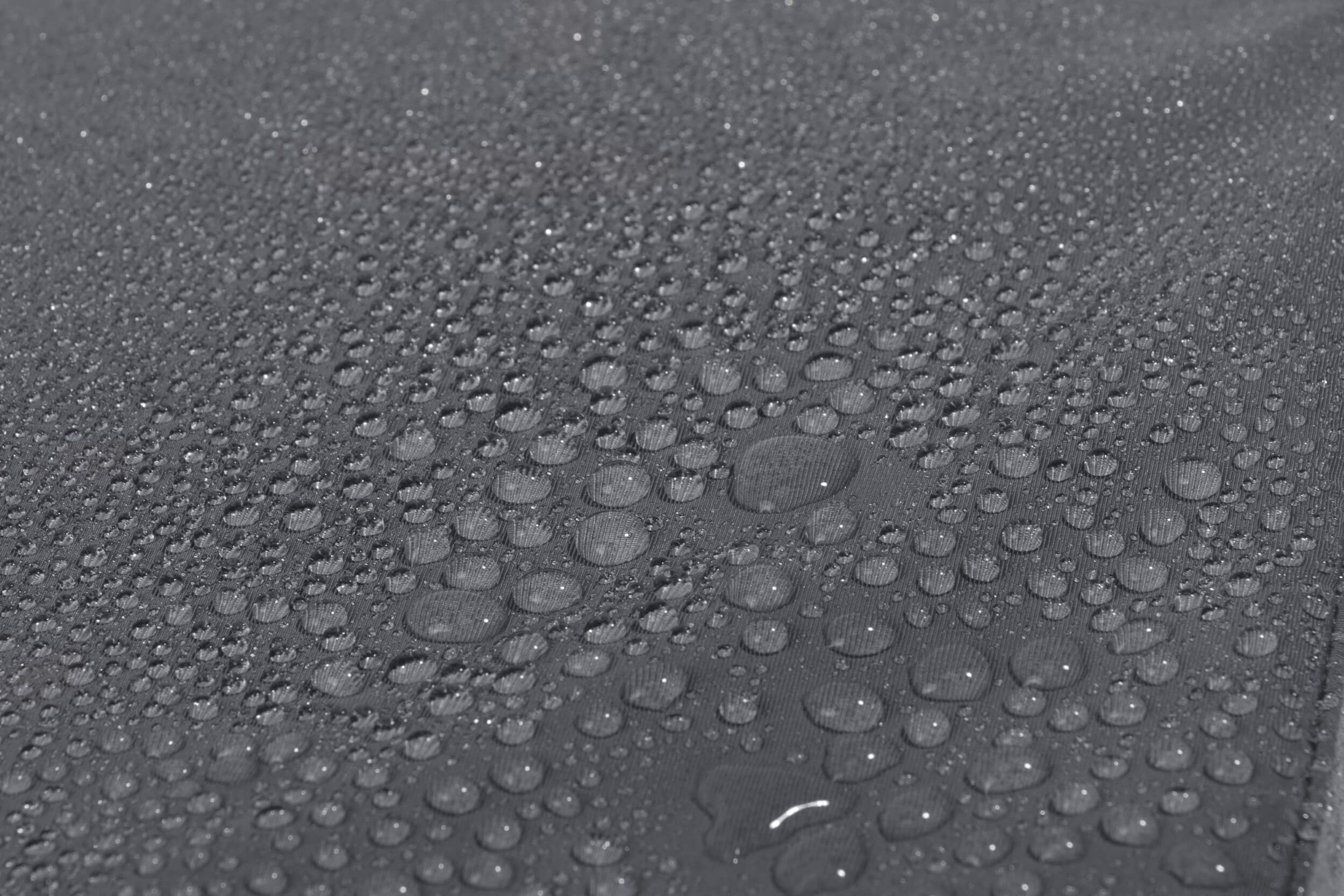 Graue, wasserabweisende Oberfläche mit Wassertropfen. Nahaufnahme.