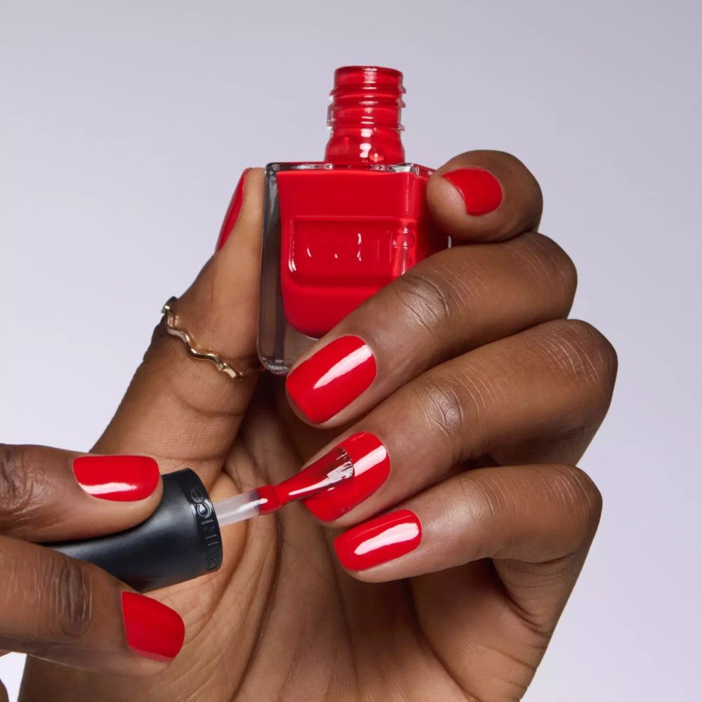 Hand lackiert Fingernägel mit rotem Nagellack. Flasche mit Pinsel ist sichtbar. Lackierte Fingernägel.