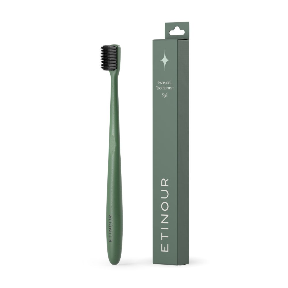 Grüne Zahnbürste und Verpackung. Verpackung mit Produktname und Logo. Zahnbürste mit schwarzem Borstenkopf.