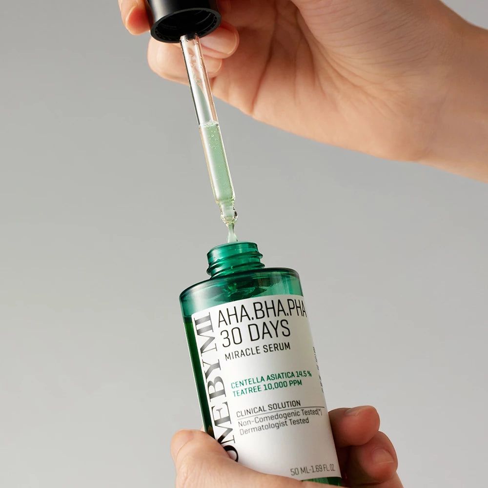 Grüne Serumflasche mit Pipette. Aufschrift: AHA.BHA.PHA 30 DAYS MIRACLE SERUM. Hände halten Flasche und Pipette.