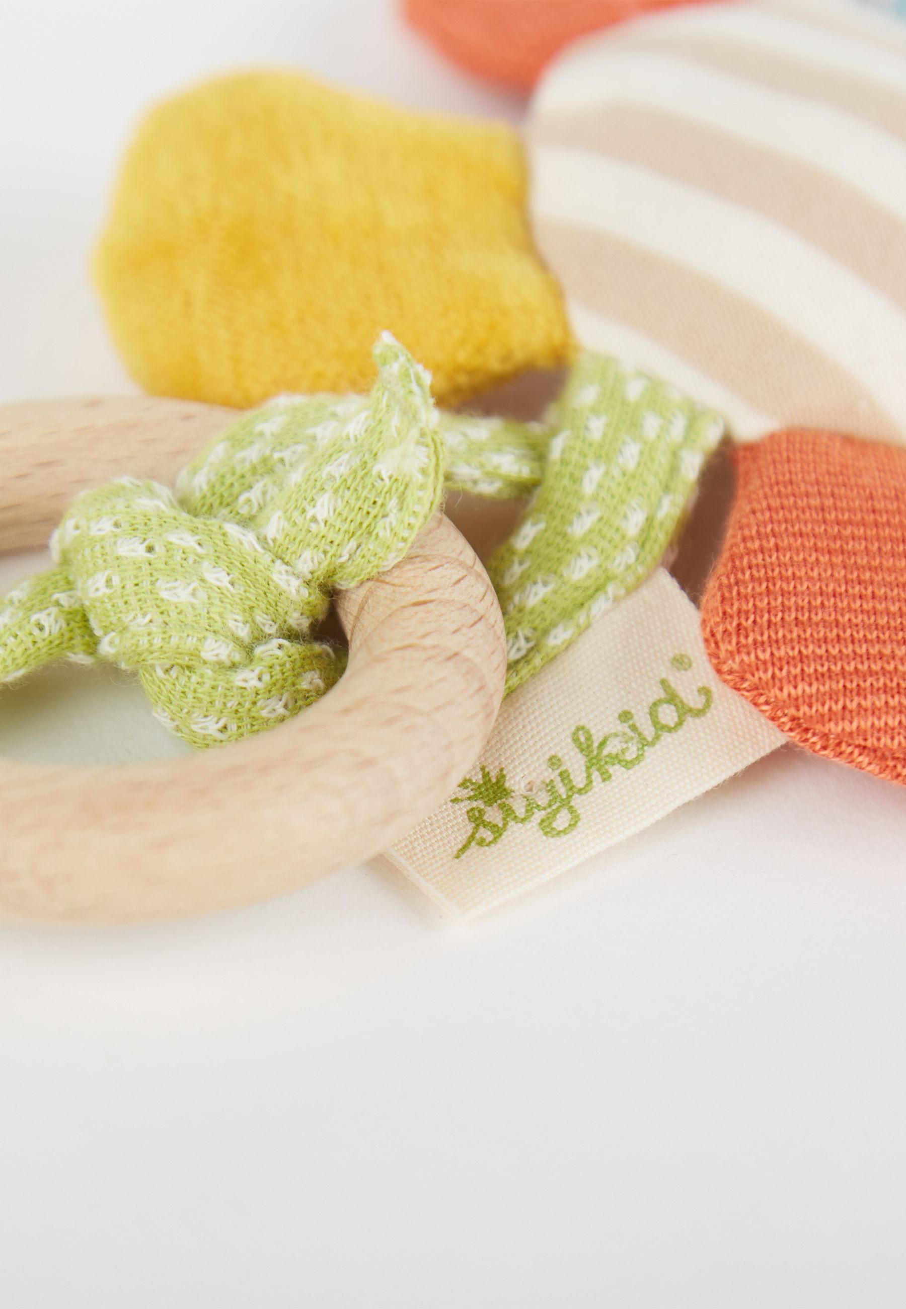 Nahaufnahme des Greiflings. Holzring, grünes Band mit Logo. Orange, gelbe Blütenblätter. Gestreifte Mitte nicht im Fokus.