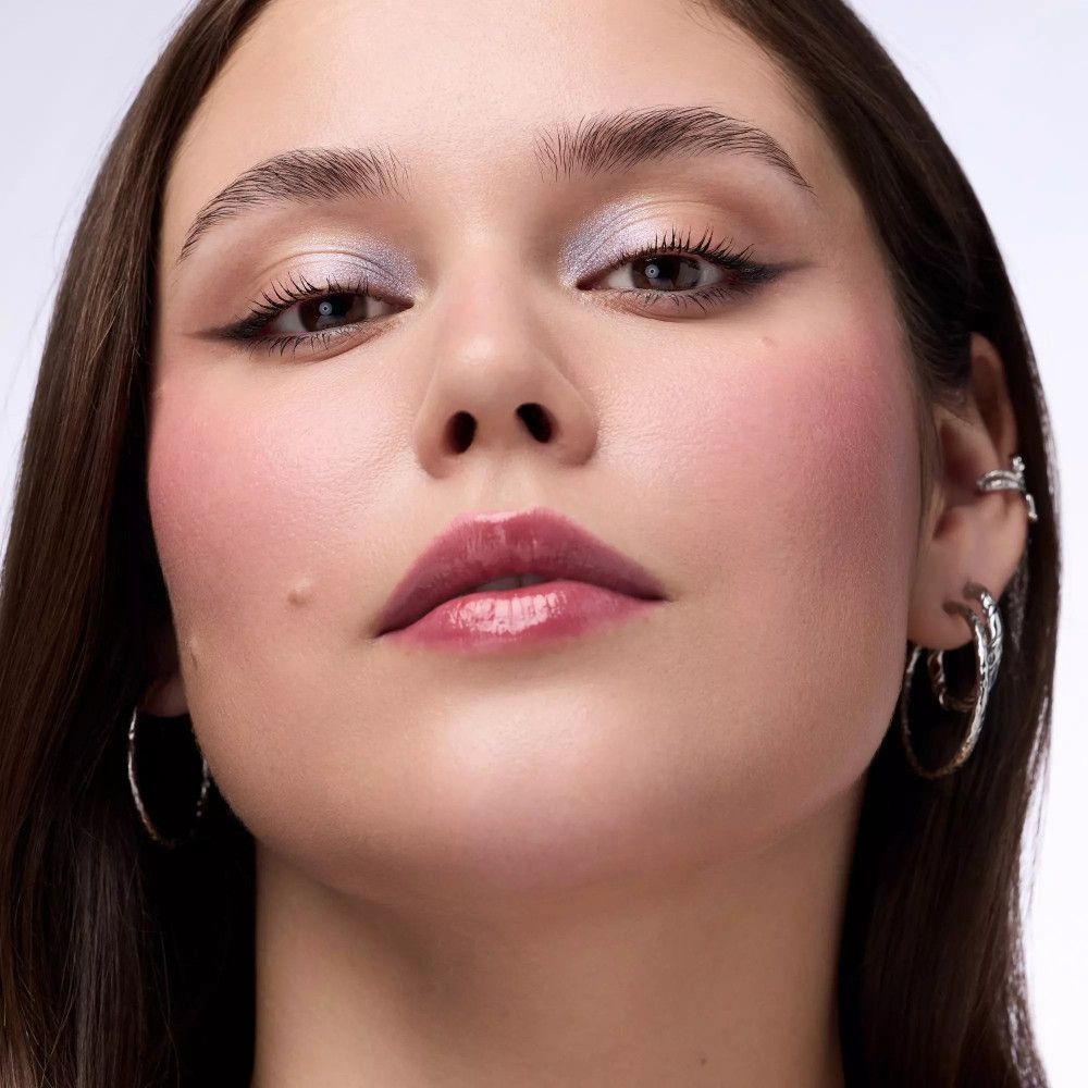 Porträt einer Frau mit silbernem Lidschatten. Lippenstift, Eyeliner und Ohrringe. Keine Marke oder Produktname sichtbar.