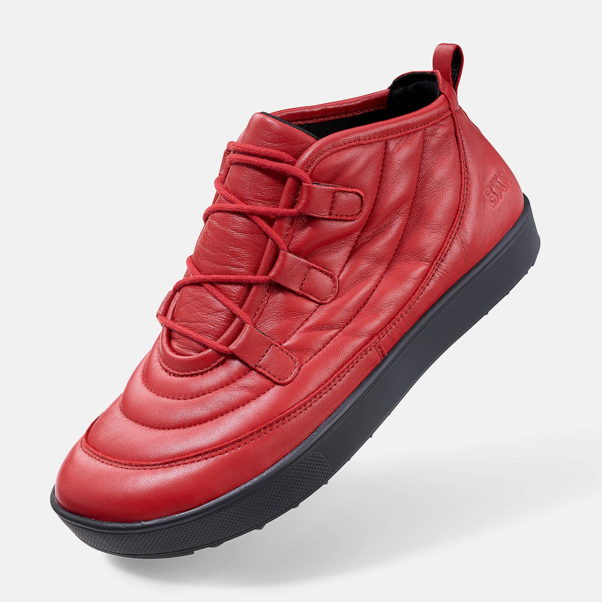 Roter Stiefelette mit Schnürung und breiter Sohle. Gepolstertes Obermaterial. Schwarze Sohle. Schuh von der Seite.