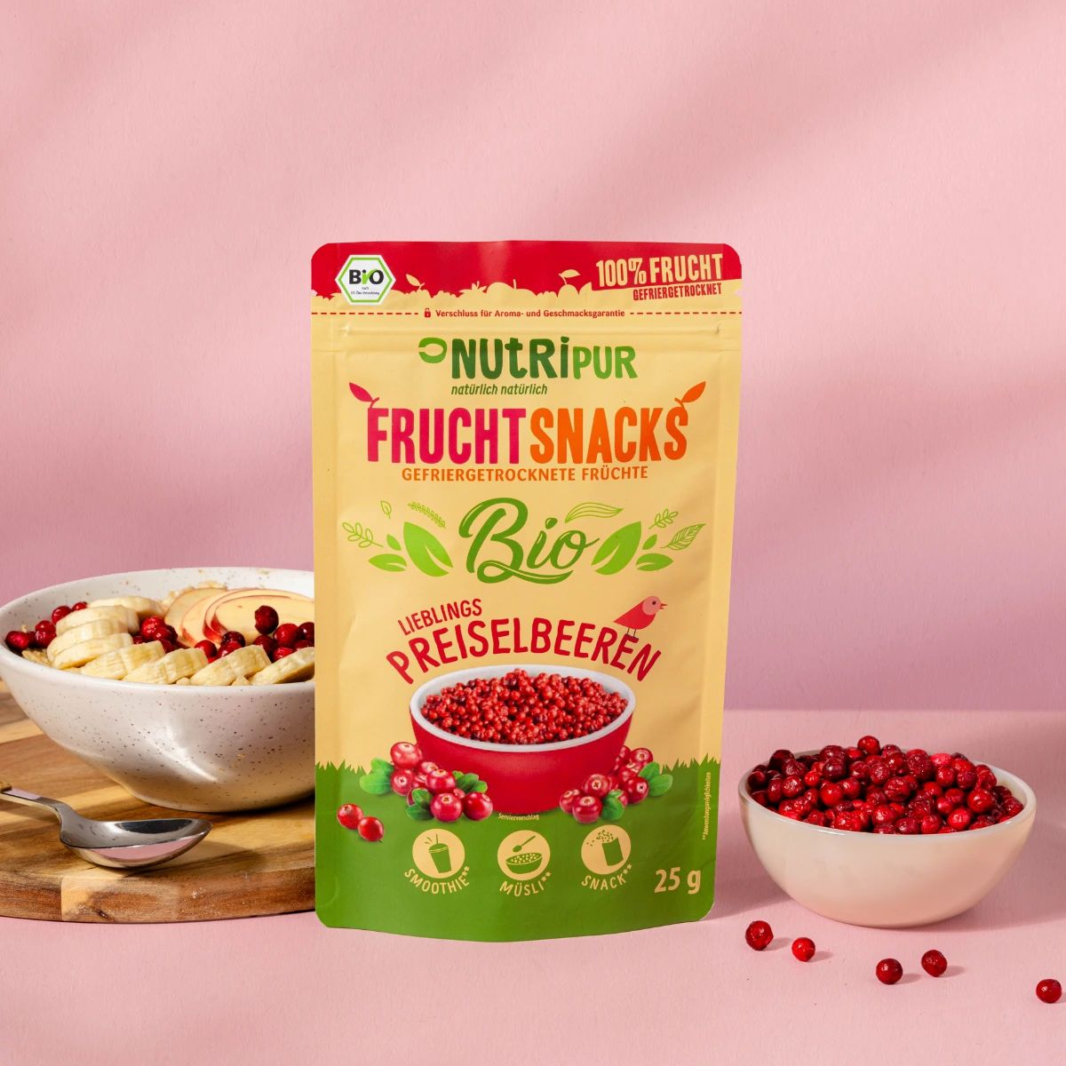 Schale mit Haferflocken, Bananen- und Apfelscheiben, Preiselbeeren. Daneben: Beutel mit Preiselbeeren, Schale mit Preiselbeeren.