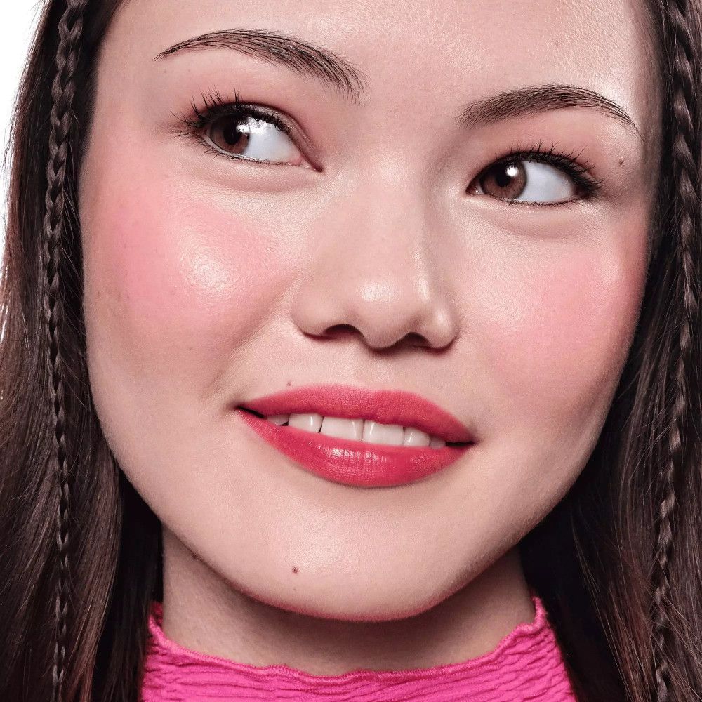 Porträt einer Frau mit rosa Lippen und Wangen. Sie trägt rosa Kleidung.