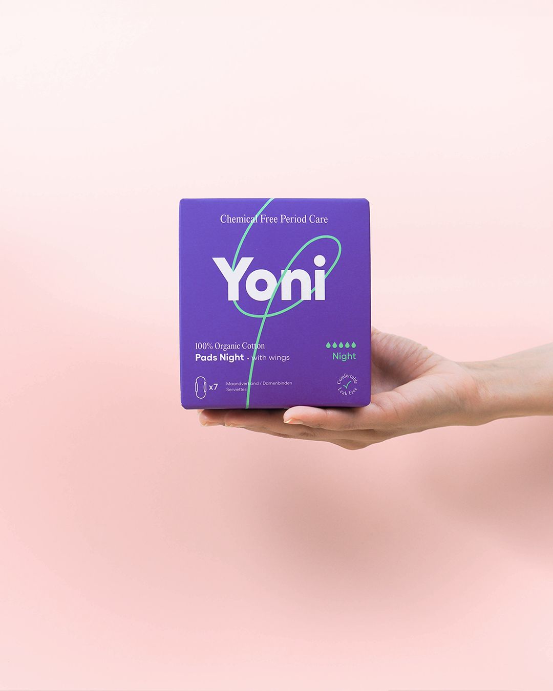 Violette Schachtel mit "Yoni"-Logo, "Night" und "100% Organic Cotton Pads". Hand hält die Verpackung vor rosa Hintergrund.
