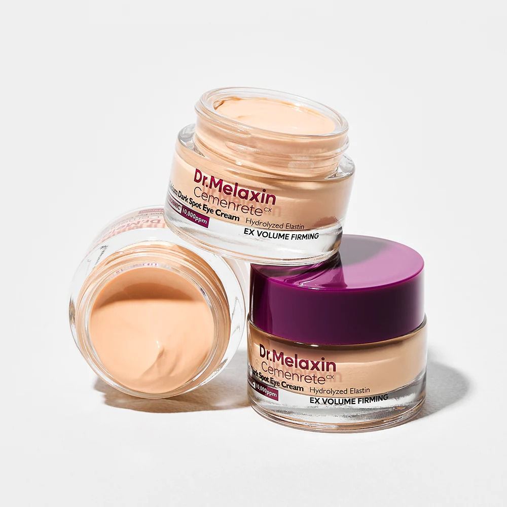 Drei Tiegel Dr.Melaxin Cemenrete Calcium Dark Spot Eye Cream. Lila Deckel, beige Creme. Weißer Hintergrund.