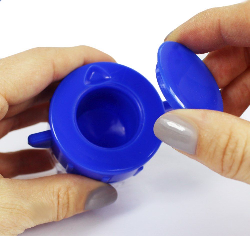 Hände halten einen blauen Tablettenmörser. Deckel wird geöffnet.