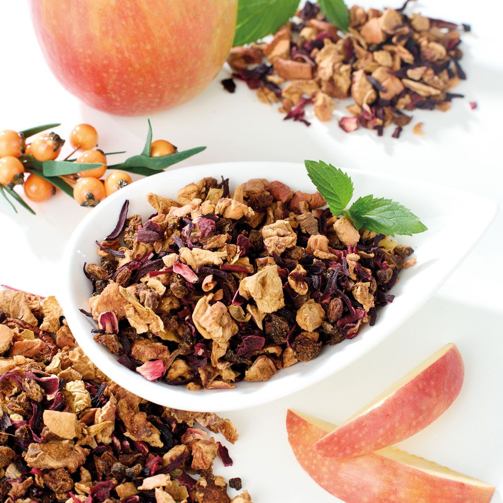 Früchtetee in weißer Schale, Äpfel und Sanddornbeeren. Minzblätter als Dekoration.