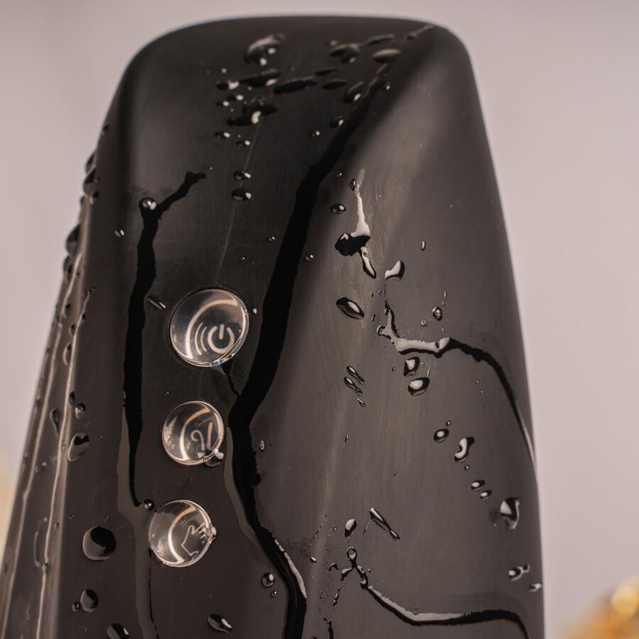 Schwarzes Gerät mit drei Knöpfen, bedeckt mit Wassertropfen. 