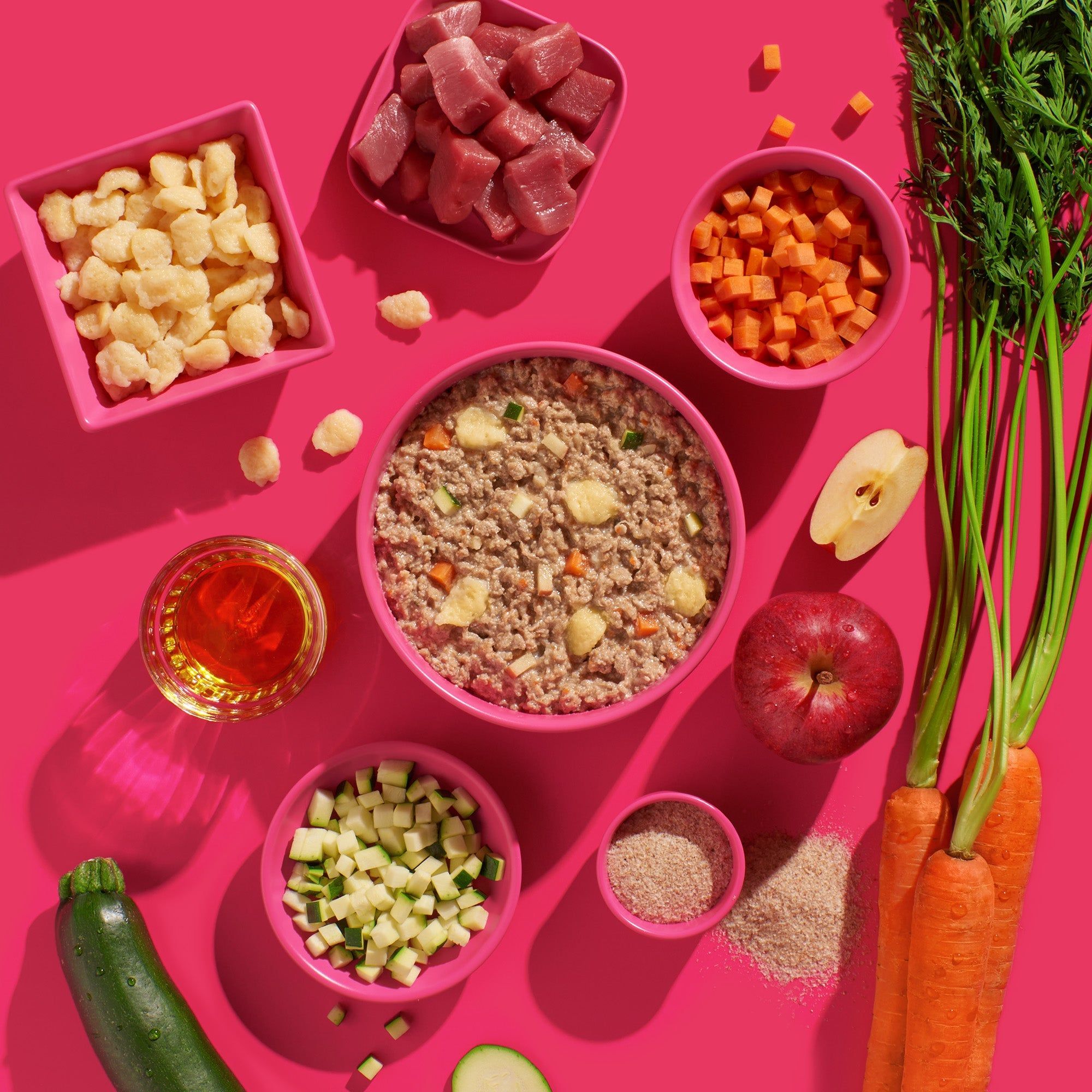 Verschiedene Zutaten für Fred & Felia FRED Schwein mit Spätzle in rosa Schalen auf pinkfarbenem Hintergrund.