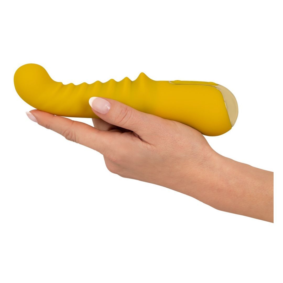 Gelber Vibrator, gehalten von einer Hand. Goldfarbenes Ende, geriffelte Oberfläche.