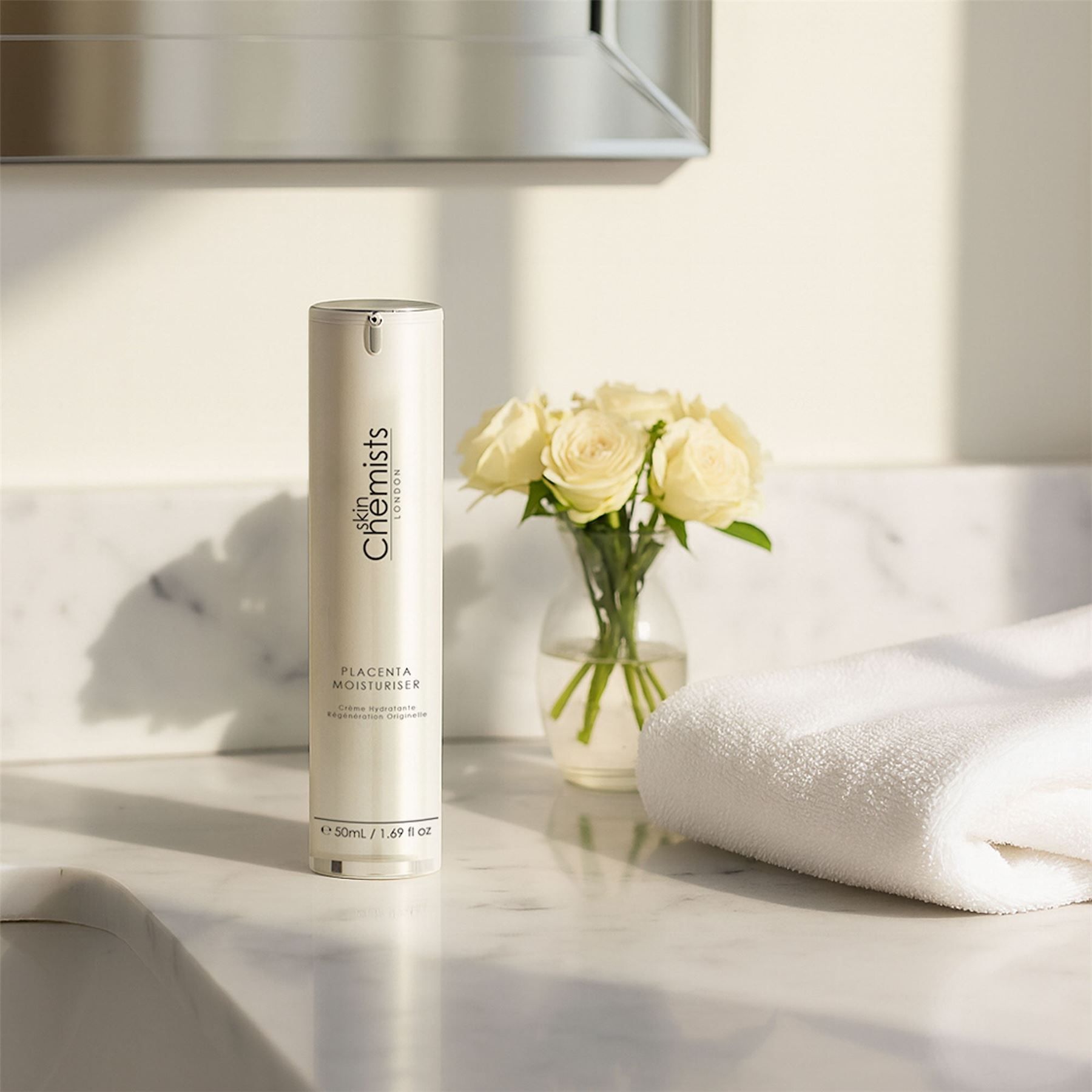 Skin Chemists Feuchtigkeitscreme neben einem Handtuch und Blumen auf einer Marmoroberfläche.