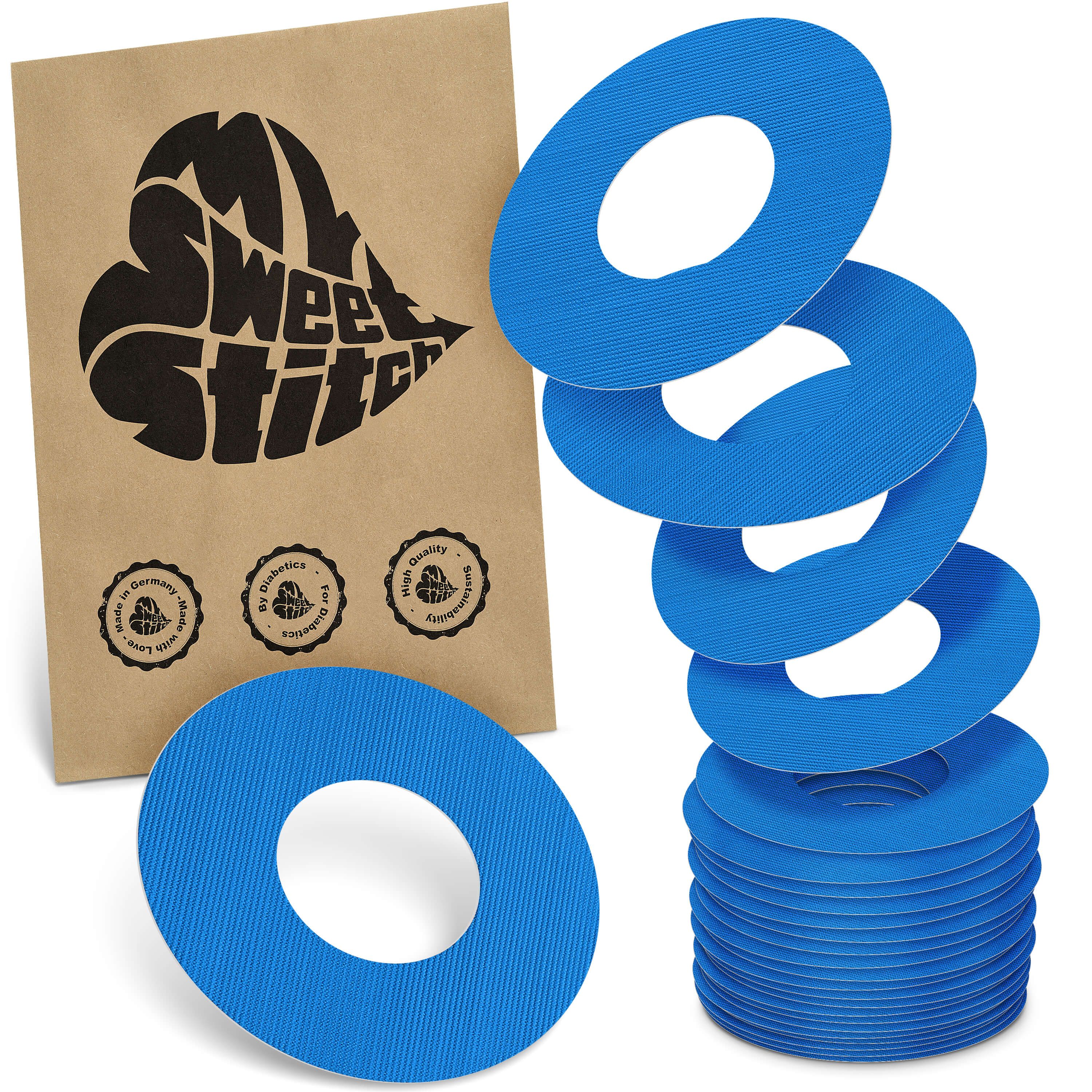 Blaue, ringförmige Pflaster. Neben einer Papiertüte mit Logo und Siegeln. Stapel und einzelne Pflaster.