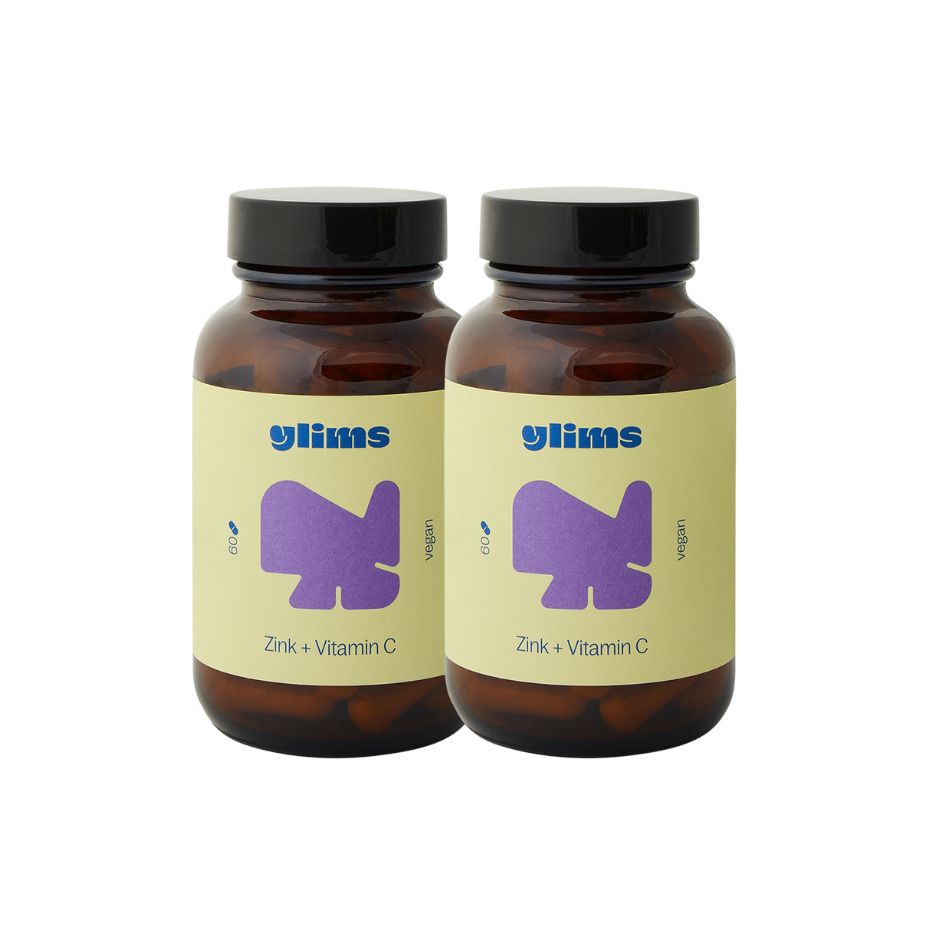 Zwei braune Glasflaschen mit schwarzen Deckeln. Etiketten mit "glims" Logo, "Zink + Vitamin C" und einem lila Design.