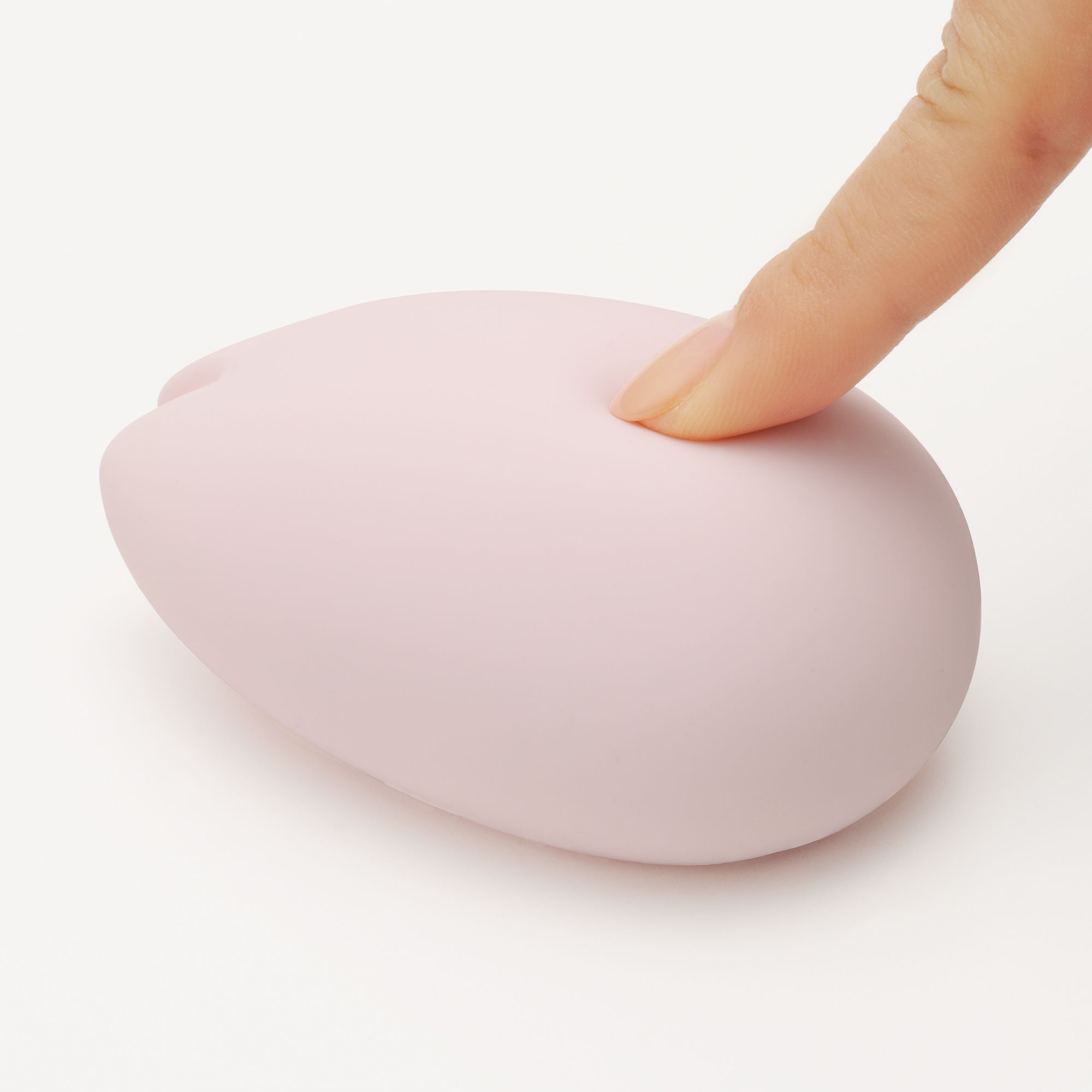 Rosa TENGA iroha SAKURA Vibrator. Finger drückt auf die Oberfläche. Glatte, weiche Textur.