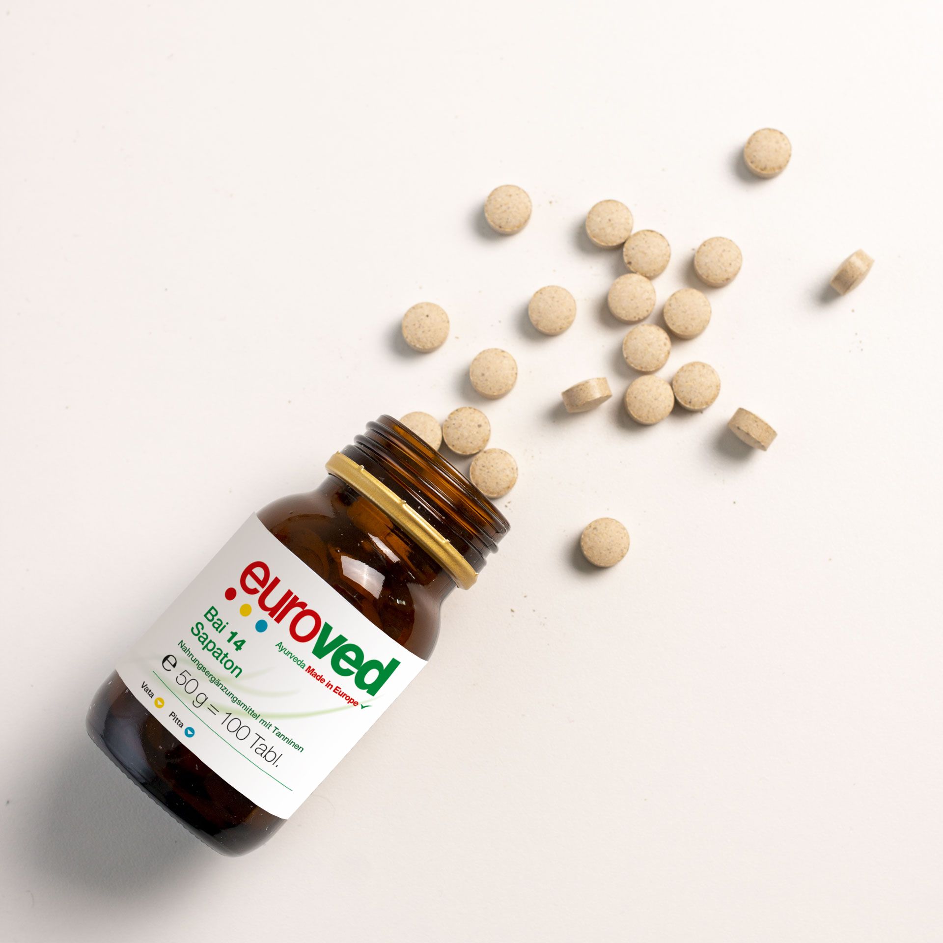 Braune Tabletten neben einer braunen Glasflasche. Auf der Flasche steht "euroved Bai 14 Sapaton".