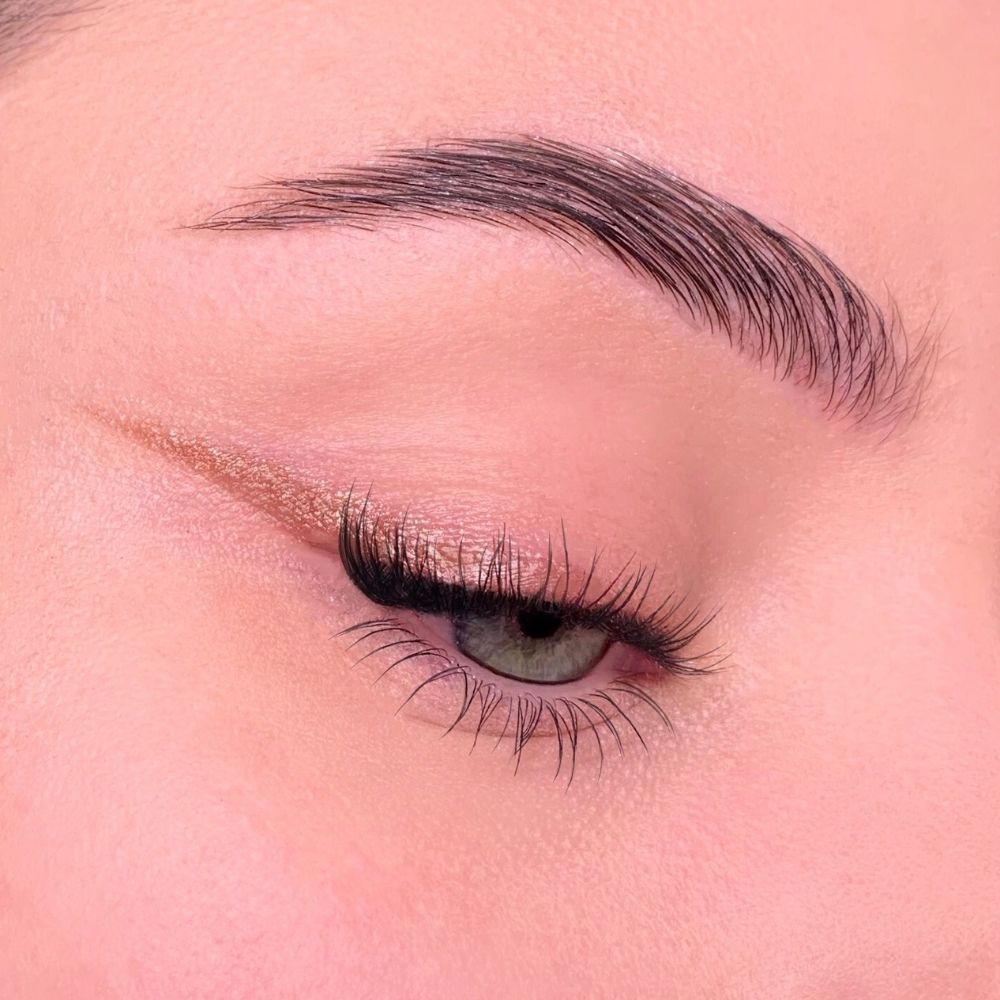 Auge mit Lidstrich. Goldfarbener Lidstrich. Wimpern verlängert.