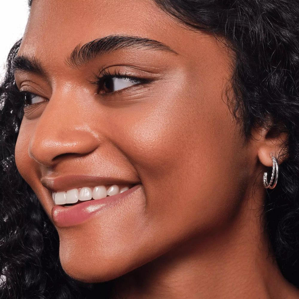 Porträt einer Frau mit glänzender Haut. Sie lächelt. Hautton: dunkel.