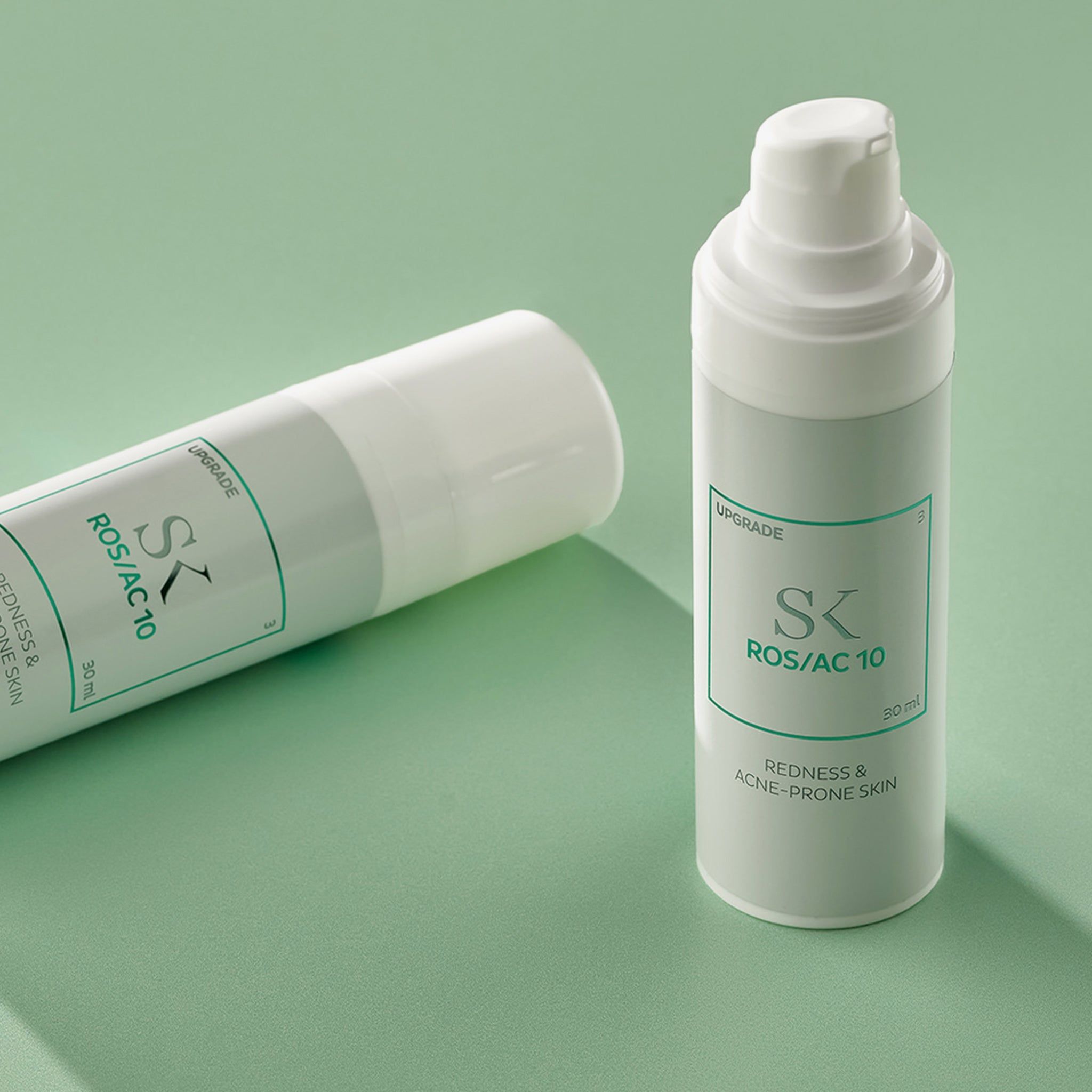 Zwei weiße Flaschen mit grünem Etikett. Aufschrift: SK ROS/AC 10, Redness & Acne-Prone Skin. 30 ml.