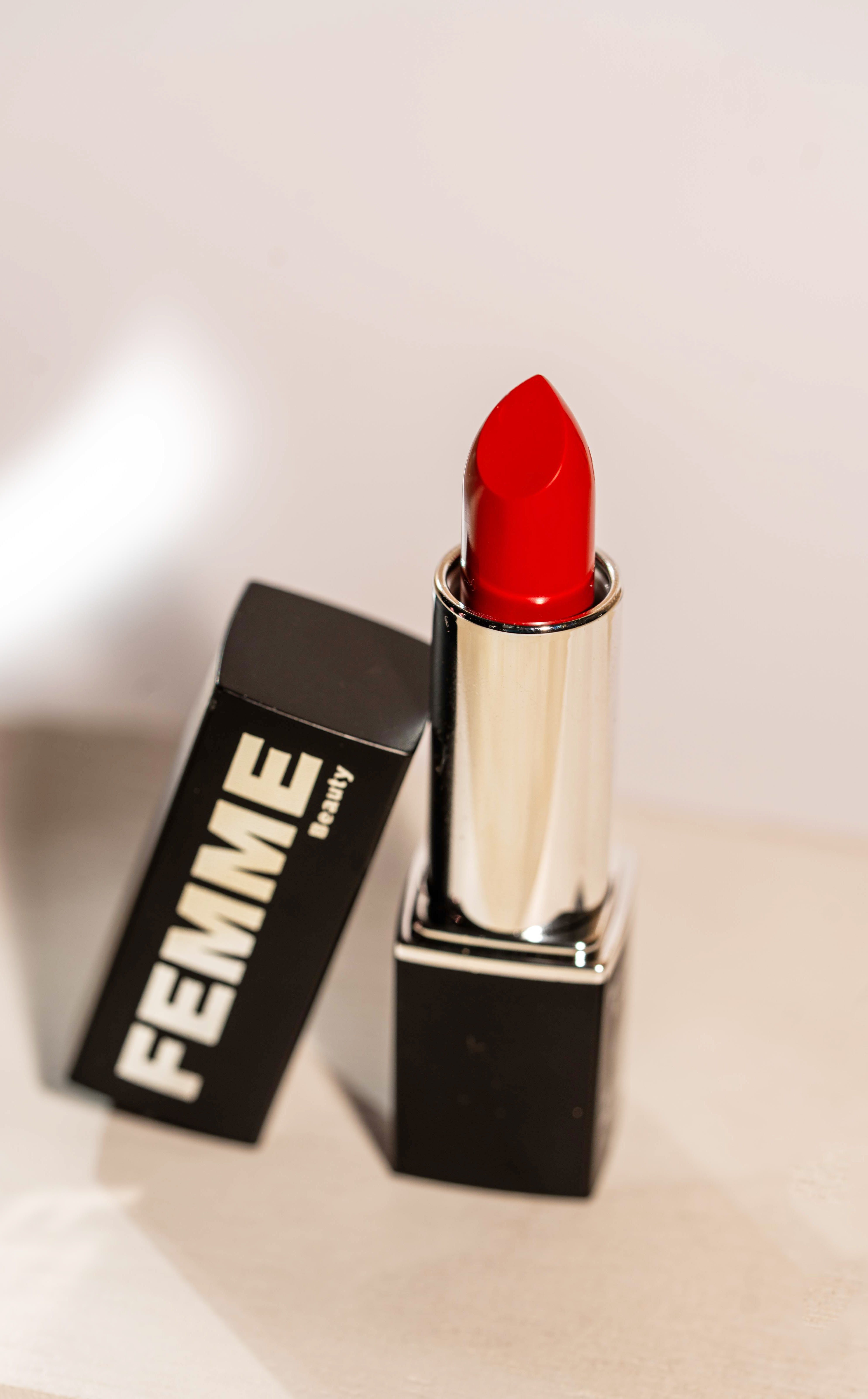 FEMME Visionary Satin Lipstick in Rot, aufrecht stehend mit abgezogener schwarzer Kappe.
