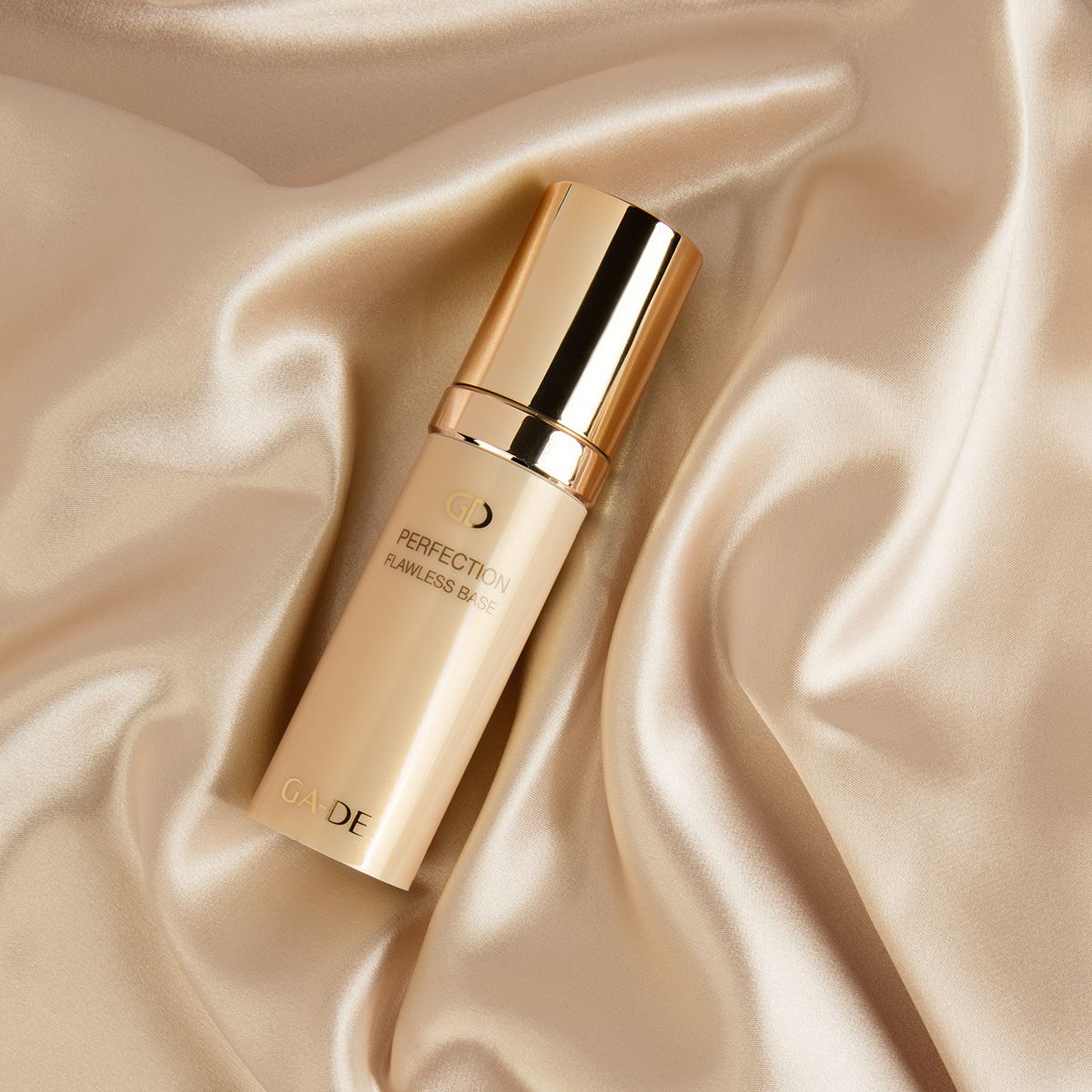 Ga-De Perfection Flawless Base. Auf goldfarbenem Stoff. Goldfarbene Flasche mit goldfarbenem Deckel.