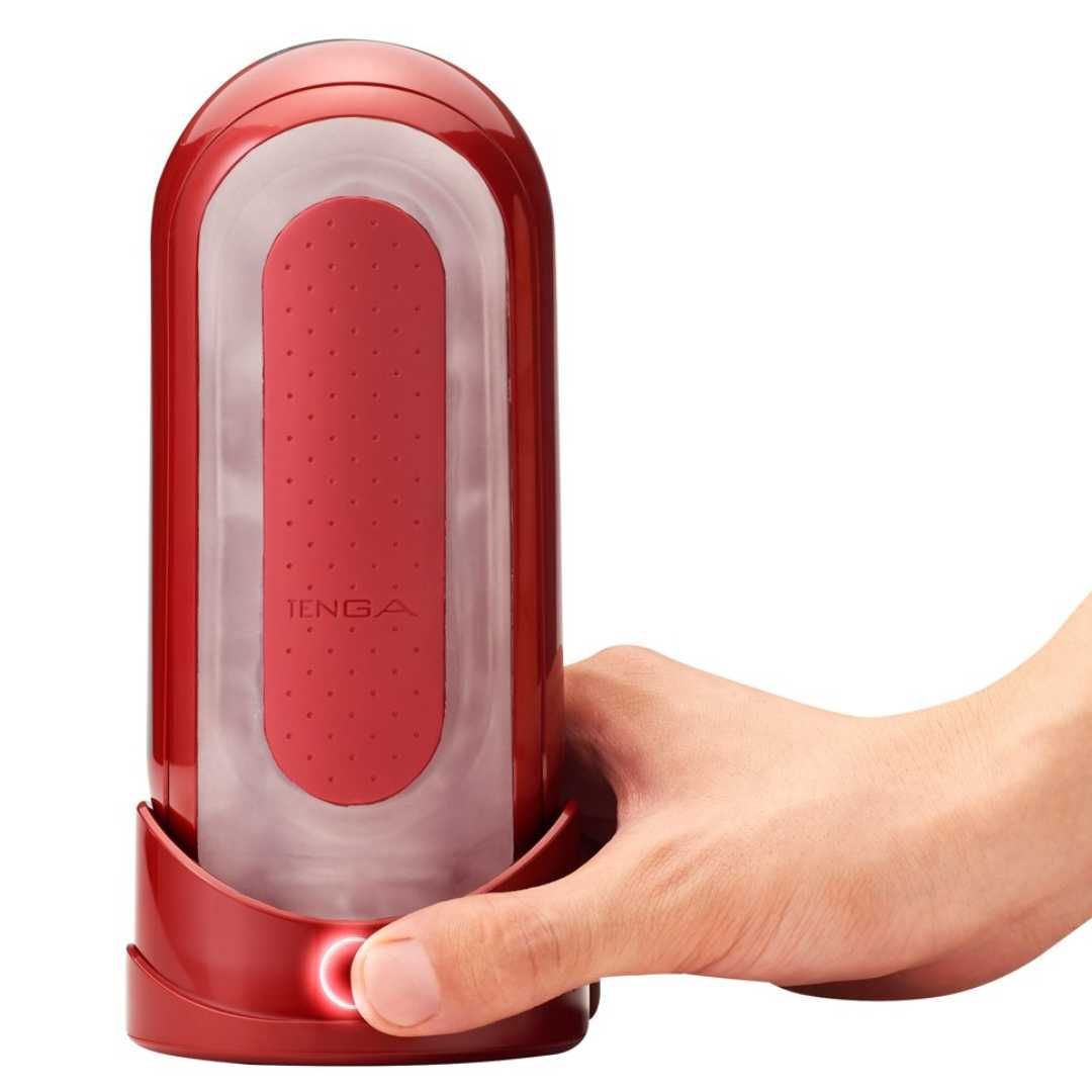 Rotes, längliches Wellness-Produkt mit weißem Innenraum. Ein Finger betätigt einen Knopf. Der Name TENGA ist sichtbar.