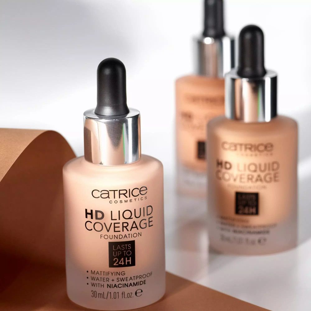 Drei Catrice HD Liquid Coverage Foundation Flaschen. Text: HD Liquid Coverage, mattierend, wasserfest, mit Niacinamid. Flaschen mit Pipetten.