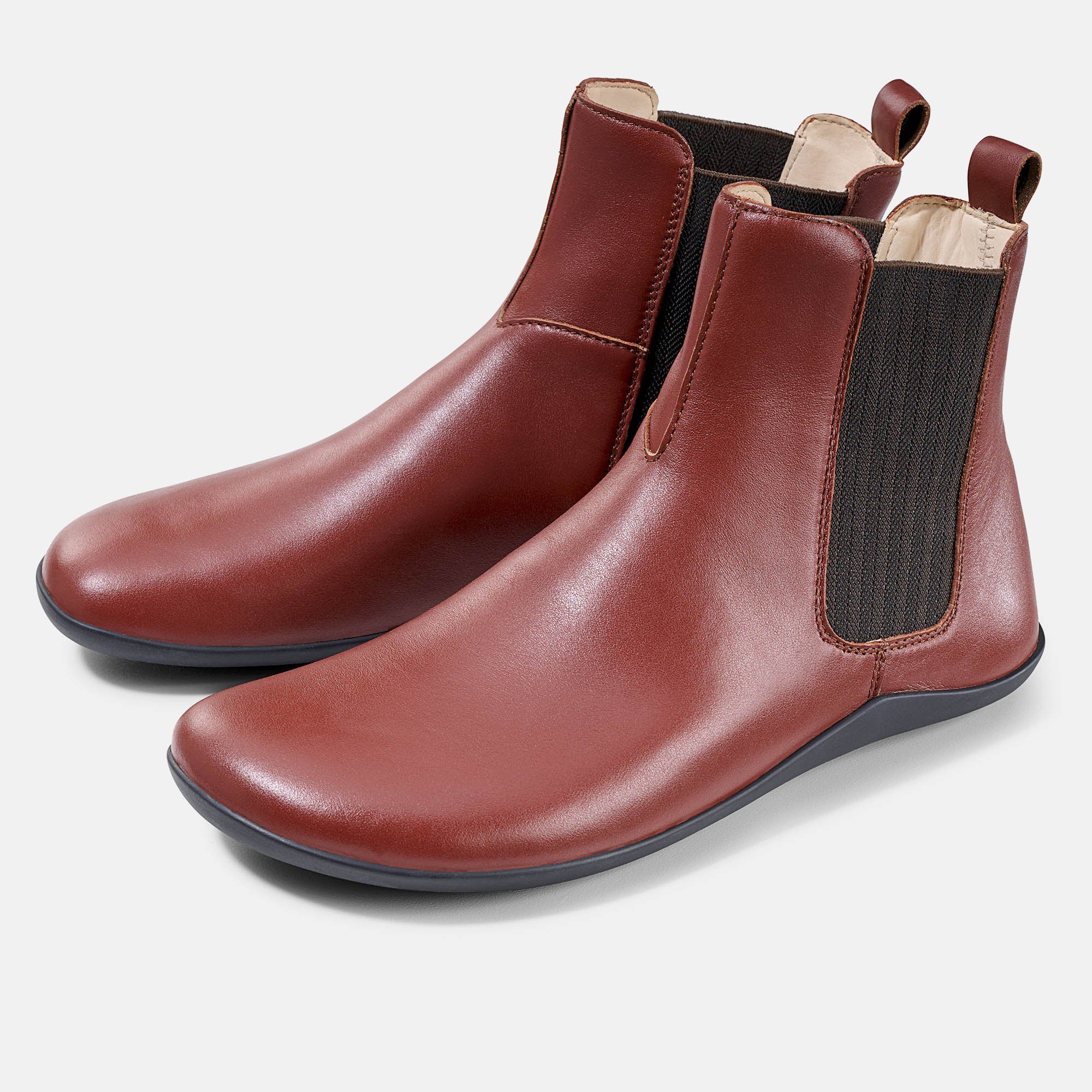 Paar rötlich-braune Stiefeletten. Elastische Einsätze an den Seiten. Schwarze Sohle. Zuglasche hinten.