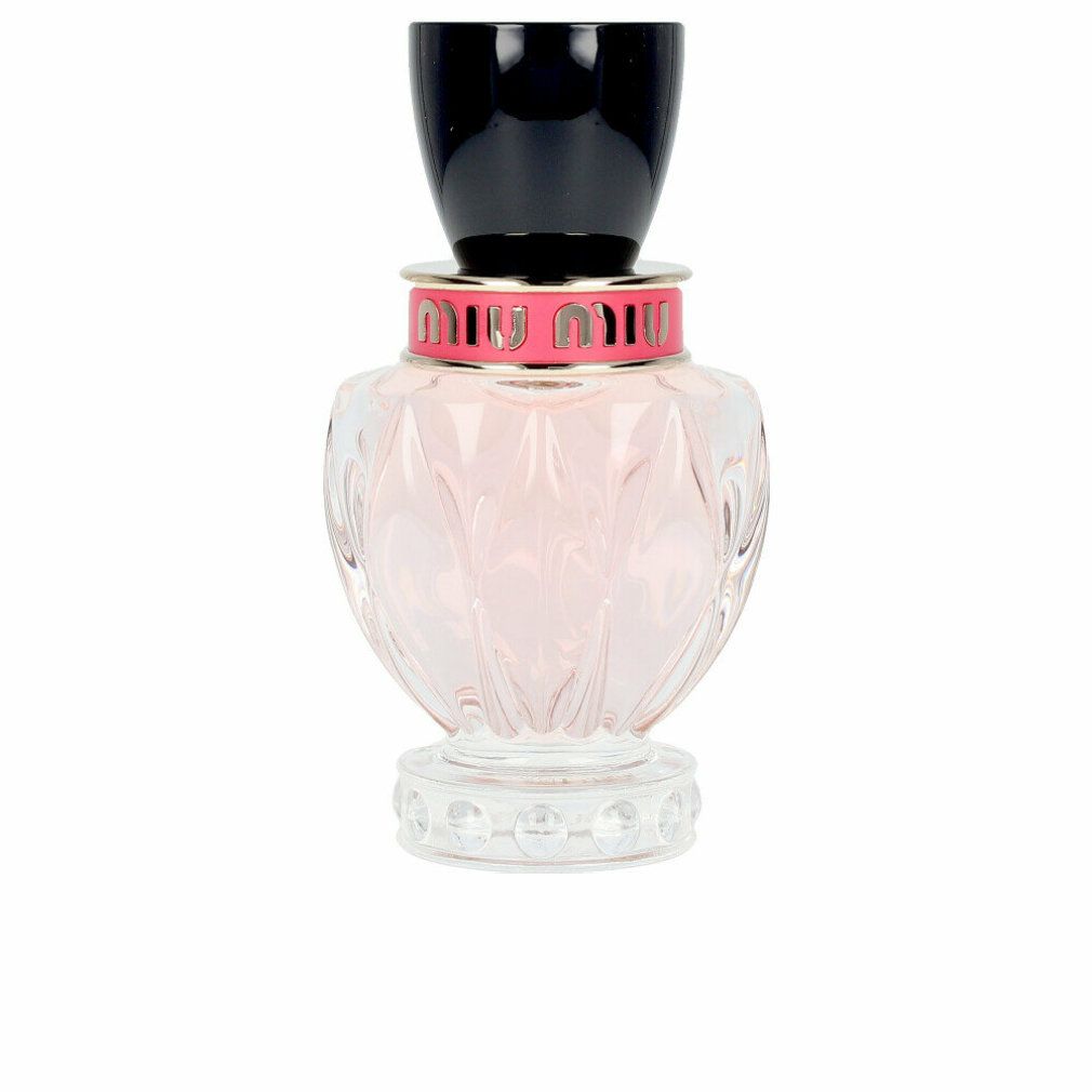 Parfümflakon mit rosa Flüssigkeit. Schwarzer Deckel, rosa und silberfarbener Ring mit Schriftzug. Klarer, geriffelter Glasbehälter.