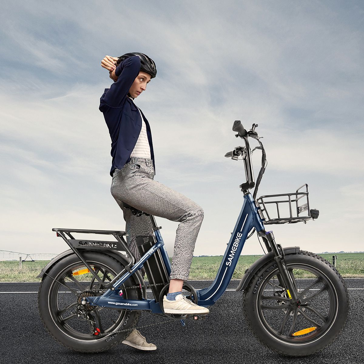Person sitzt auf blauem SAMEBIKE C05 Pro E-Bike. Helm, Straße im Hintergrund. Marke SAMEBIKE sichtbar.