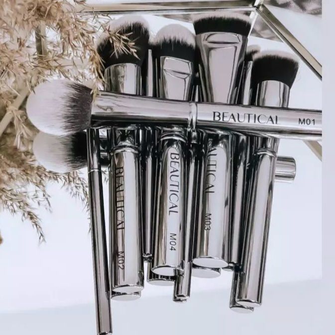 Pinselset mit silbernen Griffen. Die Marke BEAUTICAL ist sichtbar. Auf einem Spiegel.