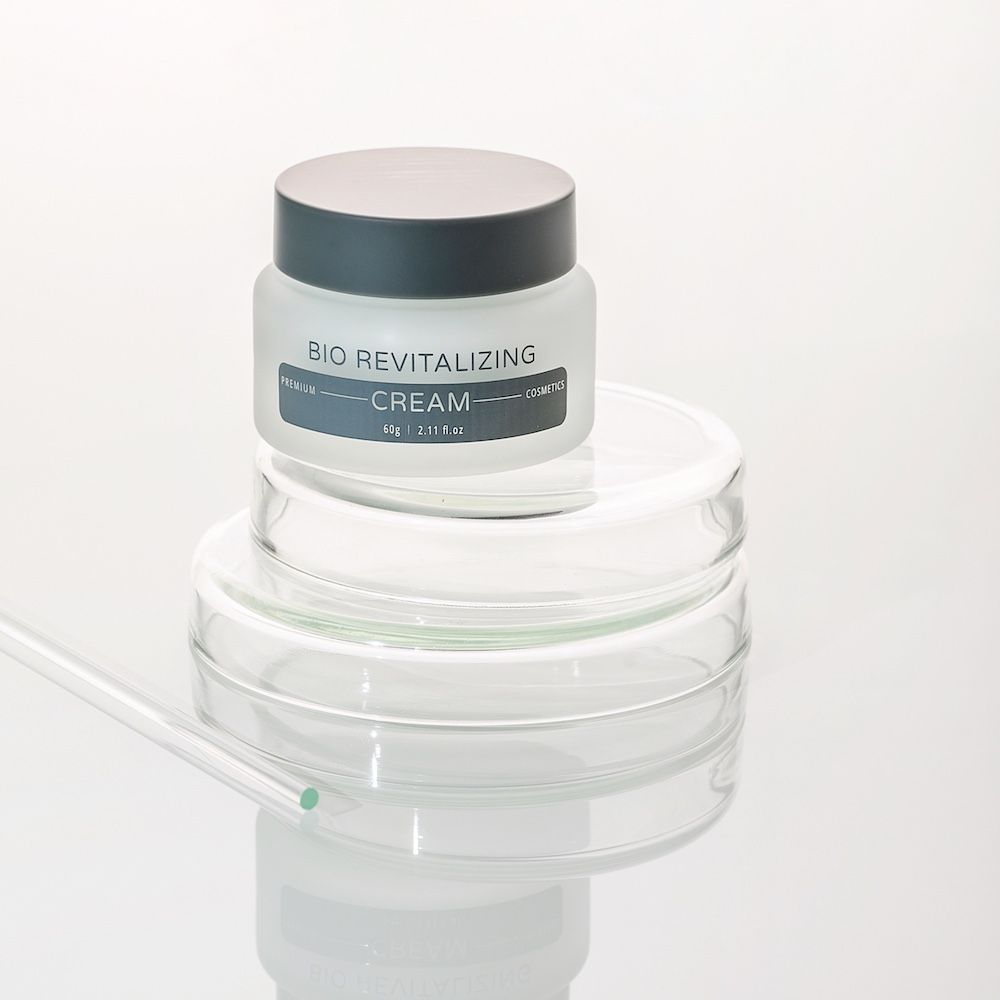 Creme-Glas mit Deckel auf Glasplatten. Aufschrift: Bio Revitalizing Cream.