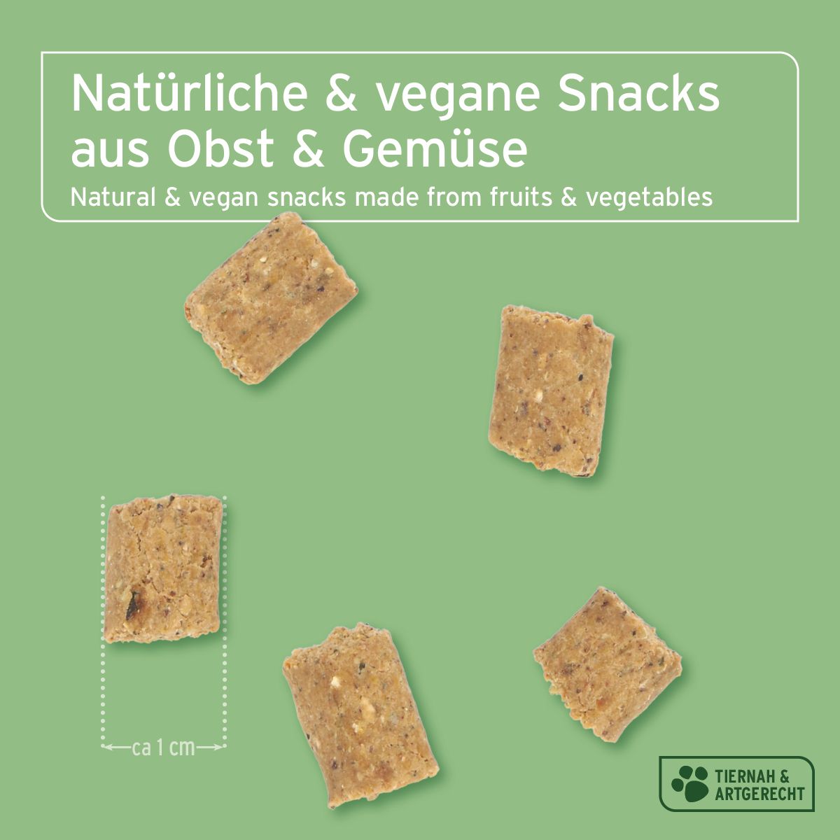 Fünf quadratische, beige Hundesnacks auf grünem Hintergrund. Aufschrift: Natürliche & vegane Snacks aus Obst & Gemüse. Ca. 1 cm groß.
