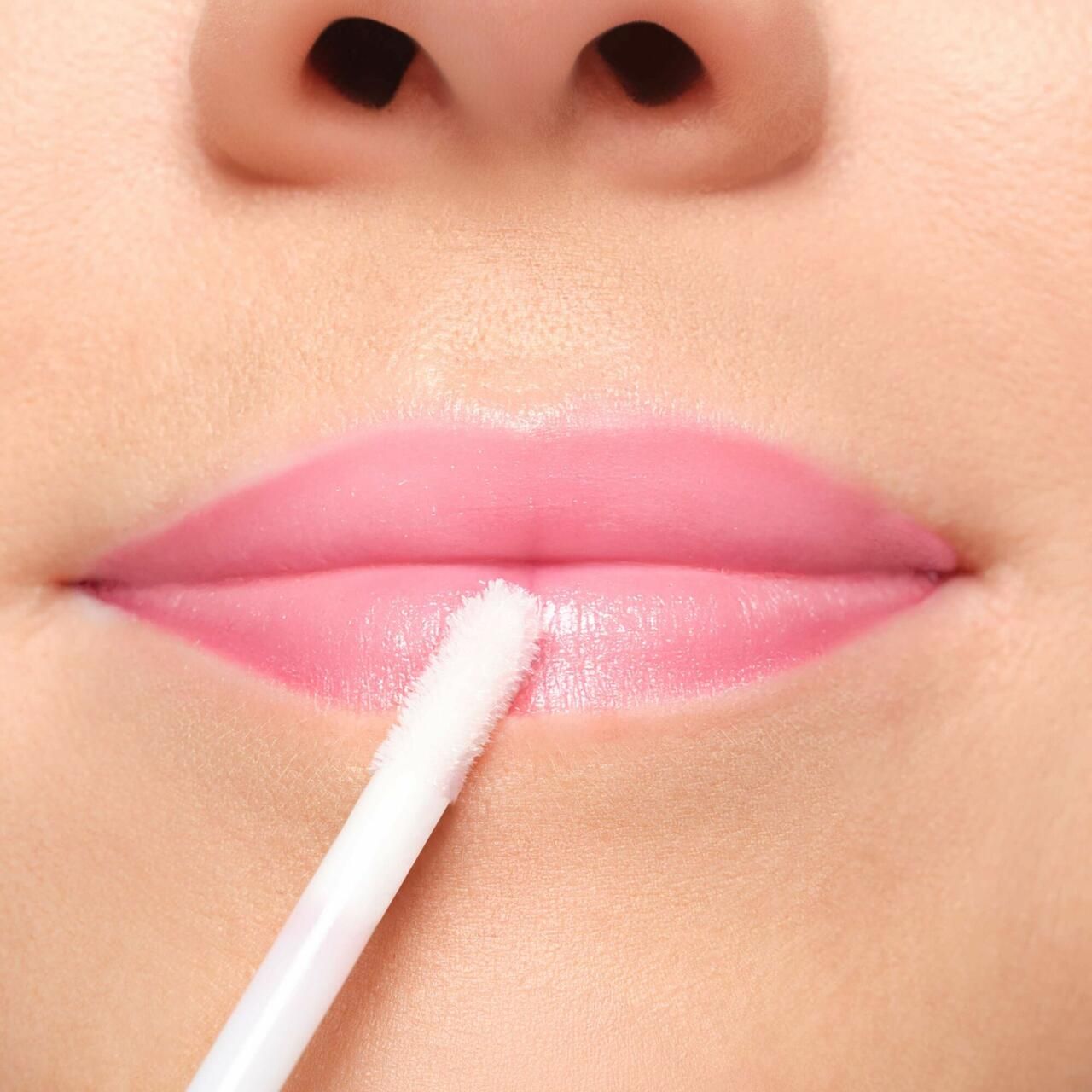Lippen mit Applikator. Rosa Lippenstift wird aufgetragen. Nahaufnahme.